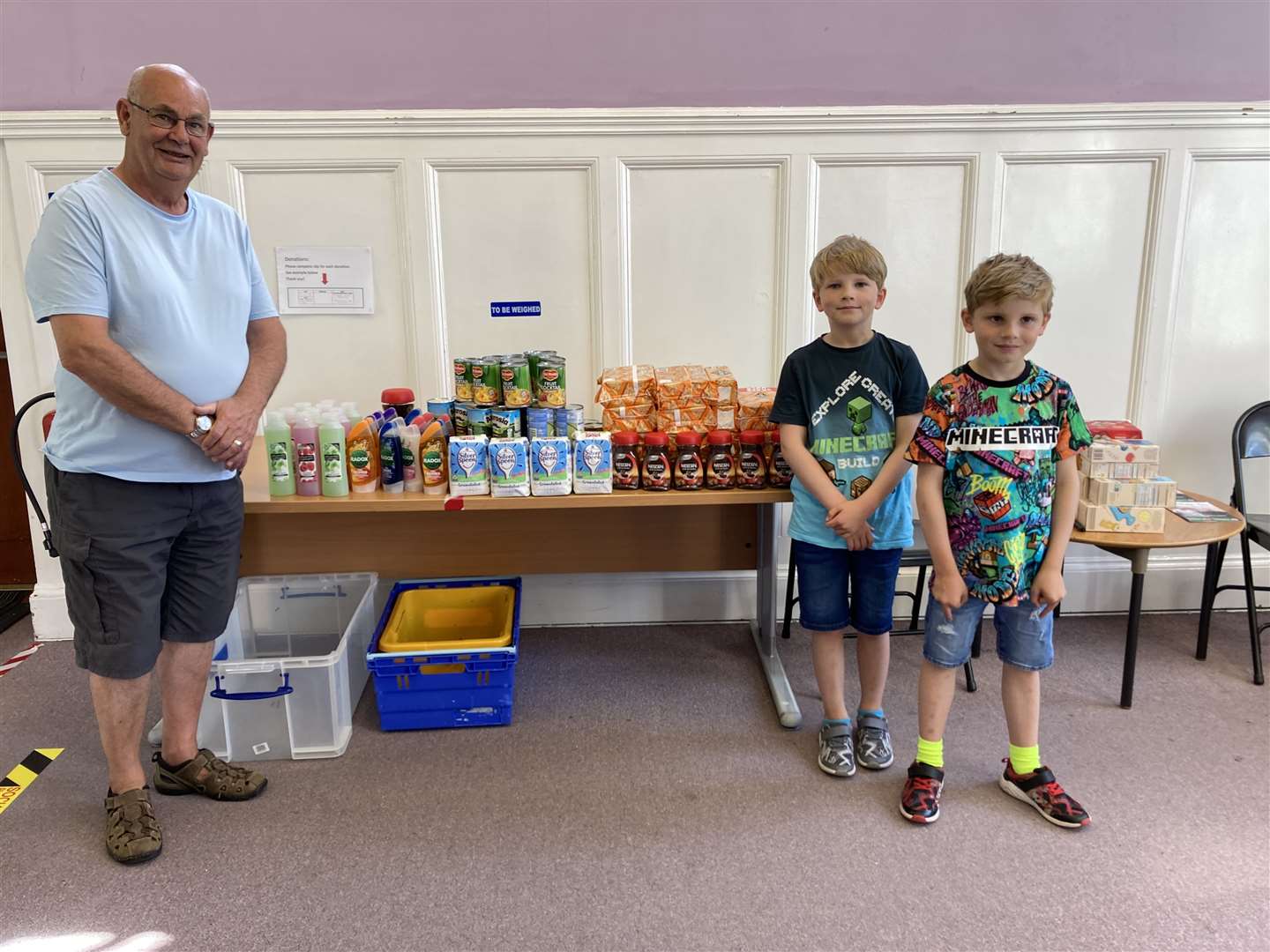 Caithness Foodbank chairman Grant Ramsay accepting the donated items from Ollie and Sammie.