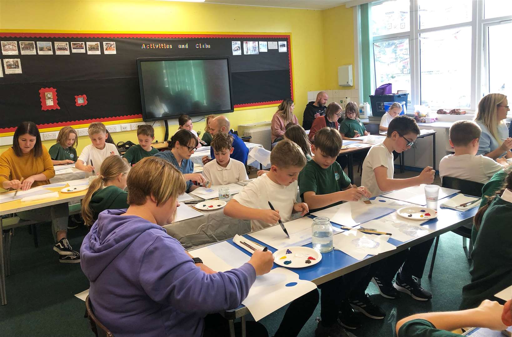 Keiss P5-P7 pupils and family members getting to work on painting waves.