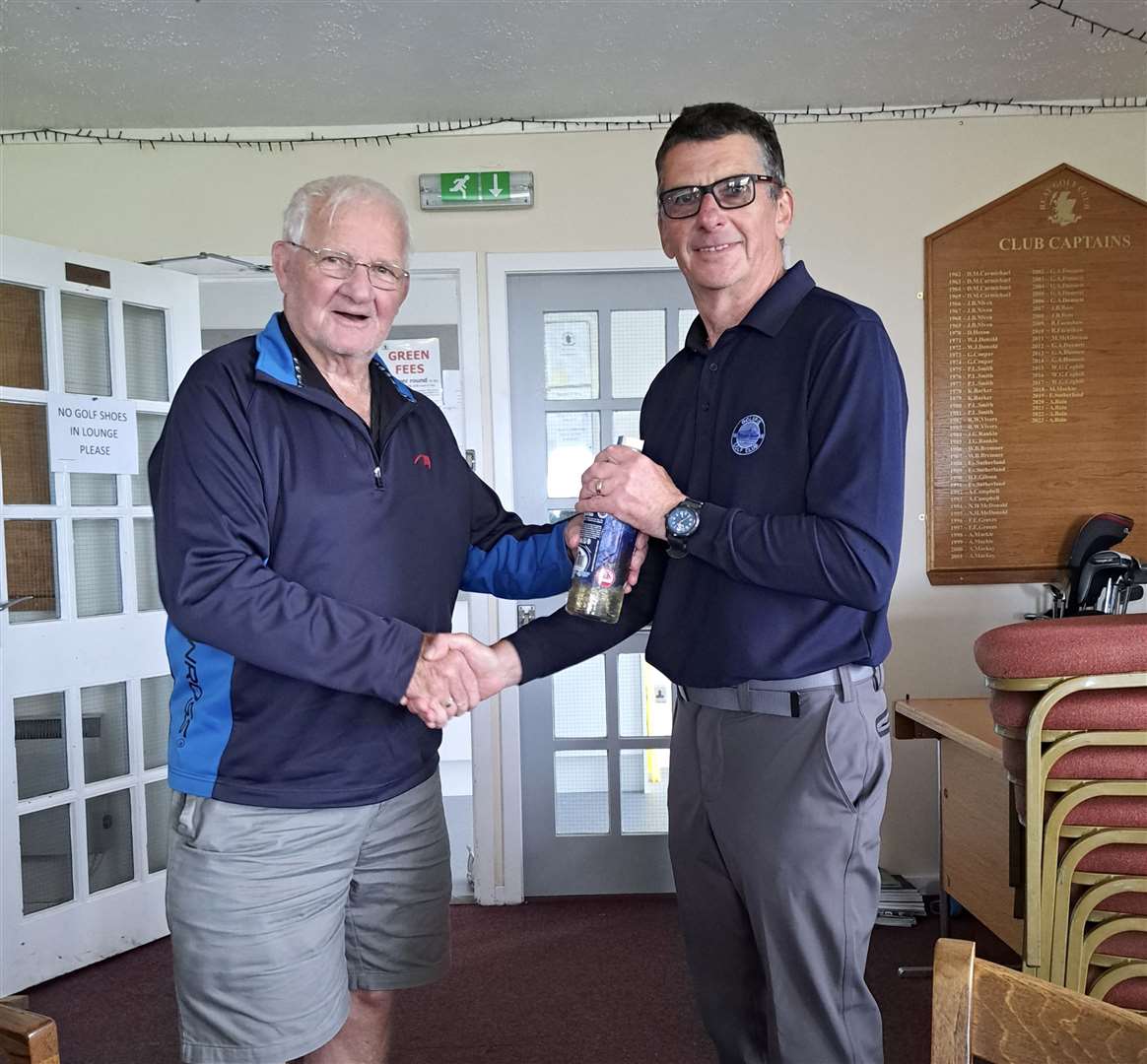 Malcolm Thomson (right) receives a bottle of North Point gin from Kenny Farmer Snr of the Reay seniors after winning the nearest-the-pin prize in the latest round of the senior Stableford competition.