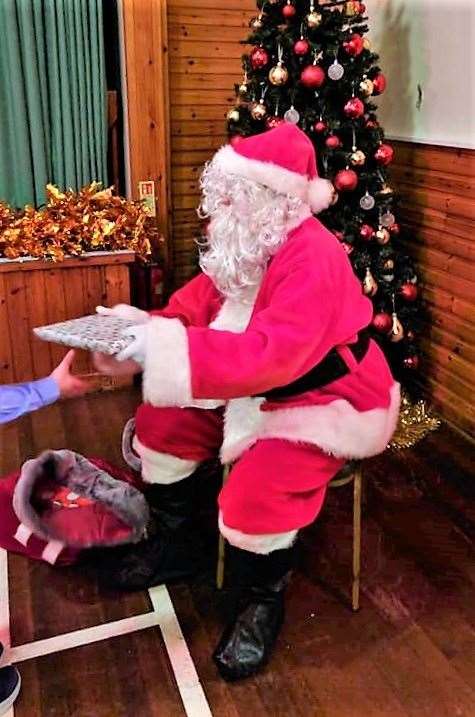 Santa gives out presents to local kids at D&S Henderson's annual Christmas Party on Saturday.