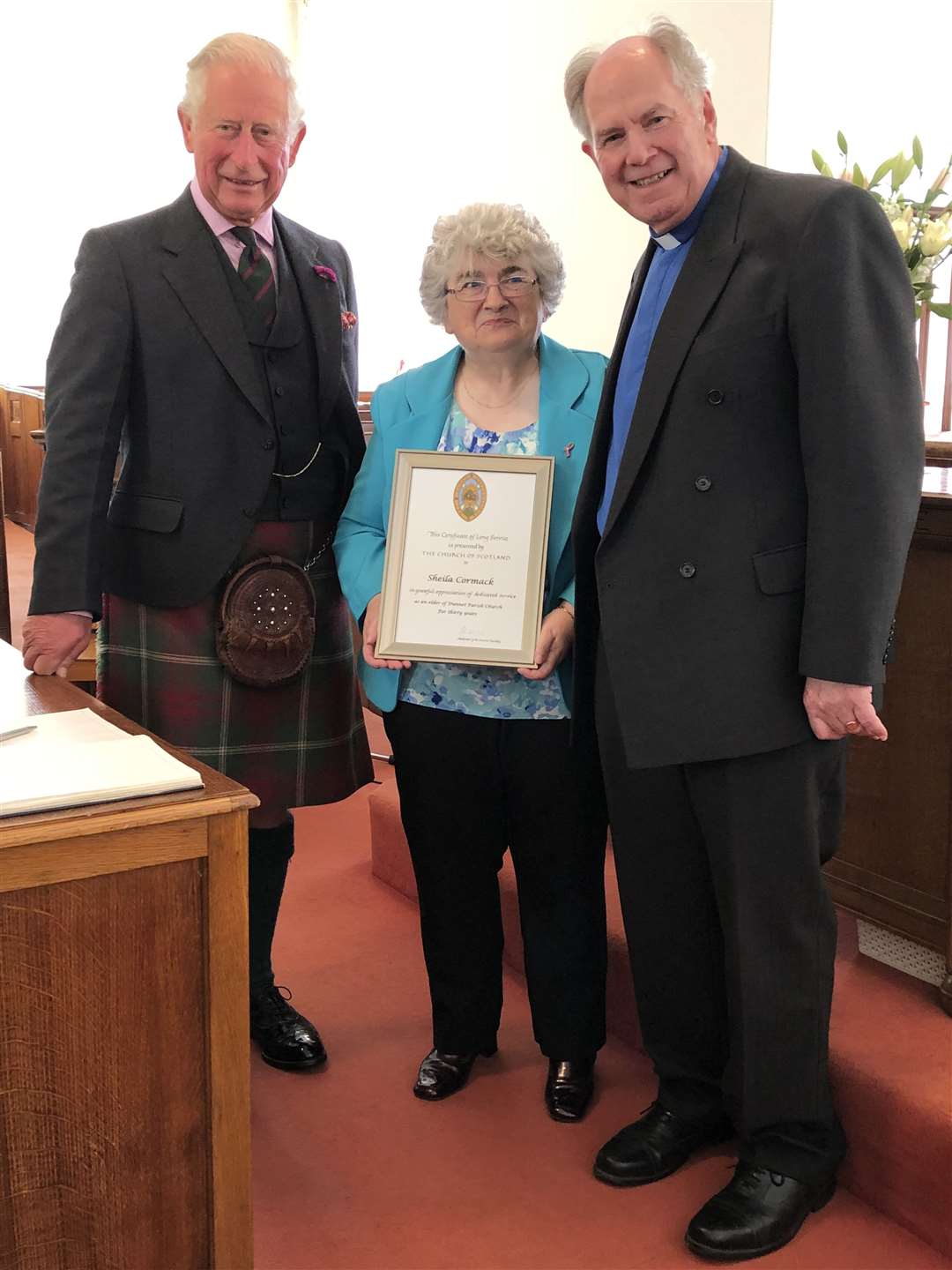 Sheila Cormack holding her long service certificate at Dunnet Church along with Prince Charles, the Duke of Rothesay, and the Rev Lyall Rennie.