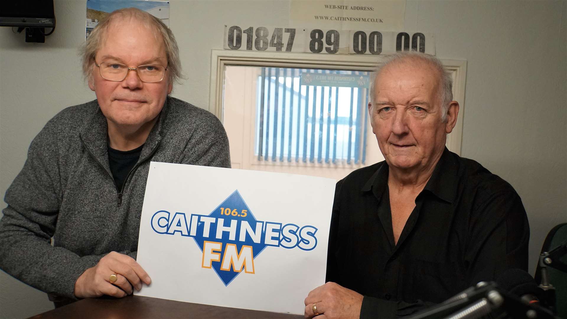 Bob Johnson, left, and Robin Young in the Caithness FM studio with the station logo and new wavelength to tune into, 106.5 FM. Pictures: DGS