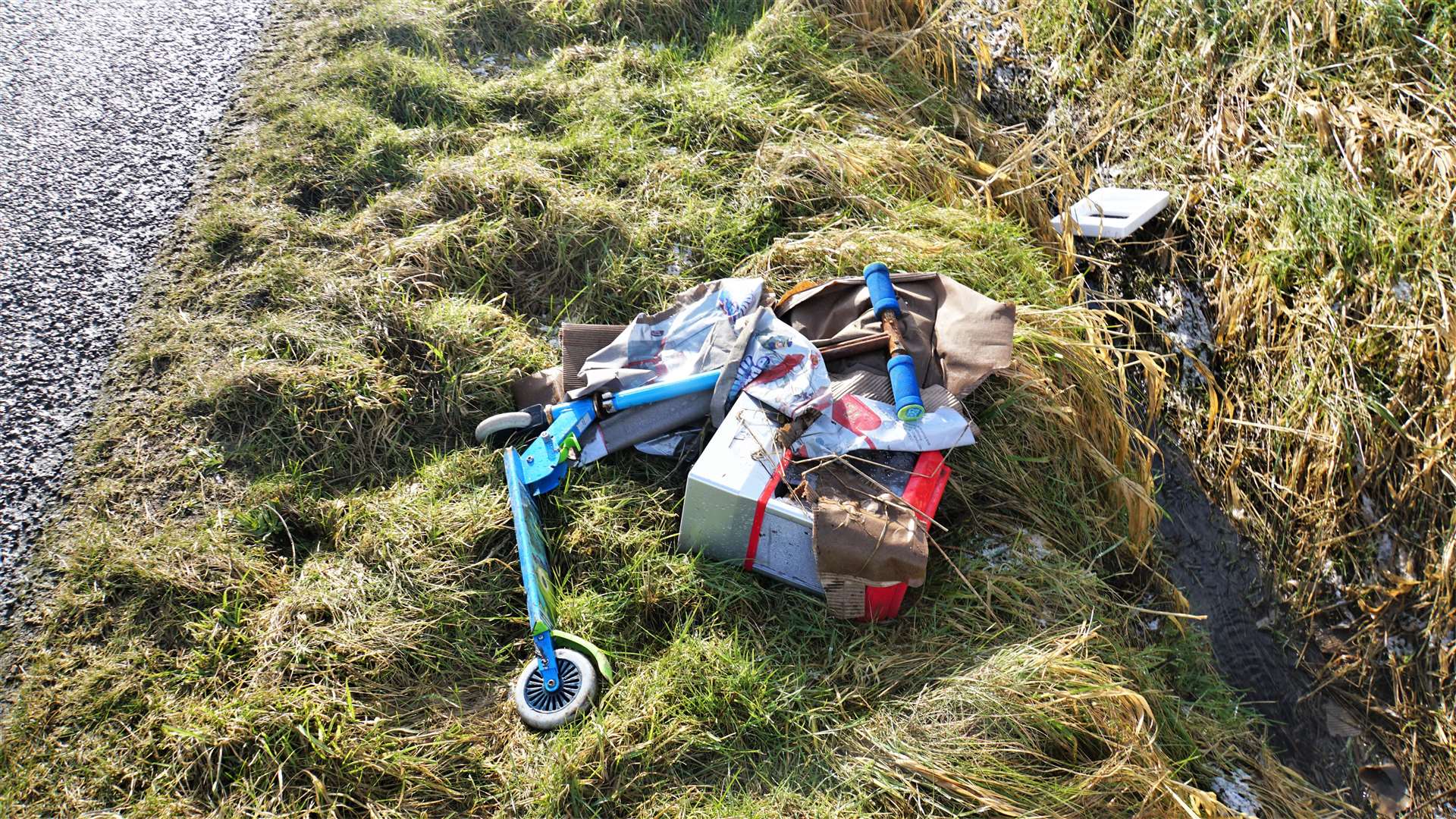 A child's scooter and various other items dumped at the side of the Tannach road.