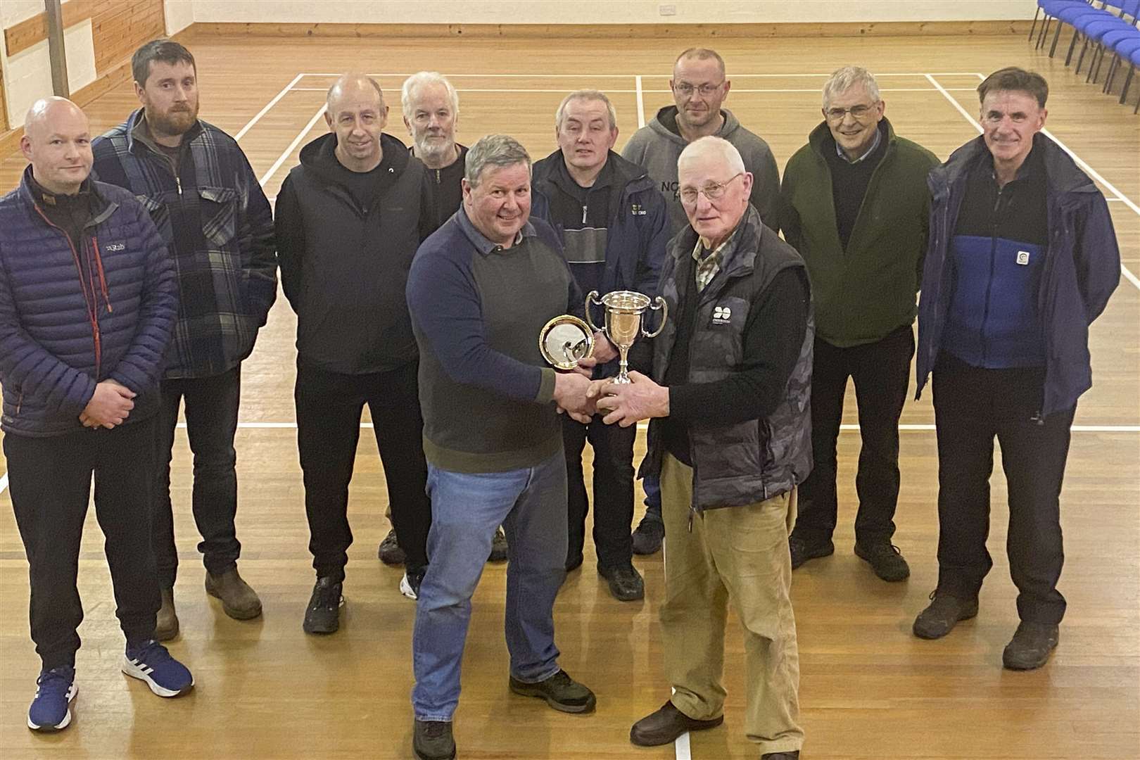 The Shearer Cup for the Caithness Indoor Shooting Championship has been won by Hugh Simpson, (left), Wick Old Stagers who is seen here receiving th trophy from Jim Manson. John Campbell, (left), Halkirk and Rognvald Brown, (2nd right), Pentland came 2nd and 3rd respectively. The competitors are selected from the top nine individual aggregates in the indoor leagues and met in Westfield to shoot a shoulder to shoulder matchplay competition to determine the winner. The other competitors are, back, from 2nd left, David Wilson, Watten, Robbie Campbell, Halkirk, Brian Young, Stevie Nicolson, David Simpson, all Wick Old Stagers and (extreme right) David Bremner, Watten.