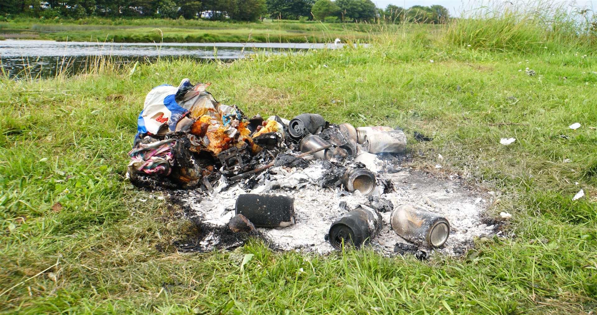 The remains of a camp fire with burnt cans and food wrappings left behind after the family vacated the area.