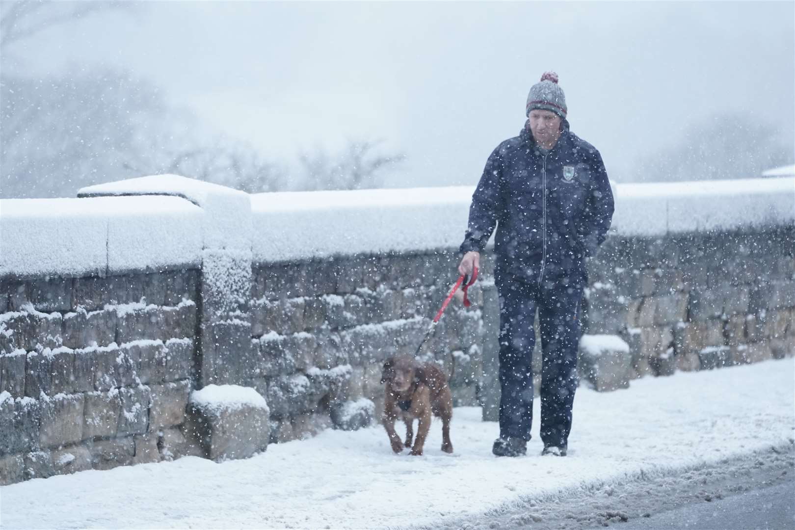 A dog walker makes his way through the snow in Hexham, Northumberland (Owen Humphreys/PA)