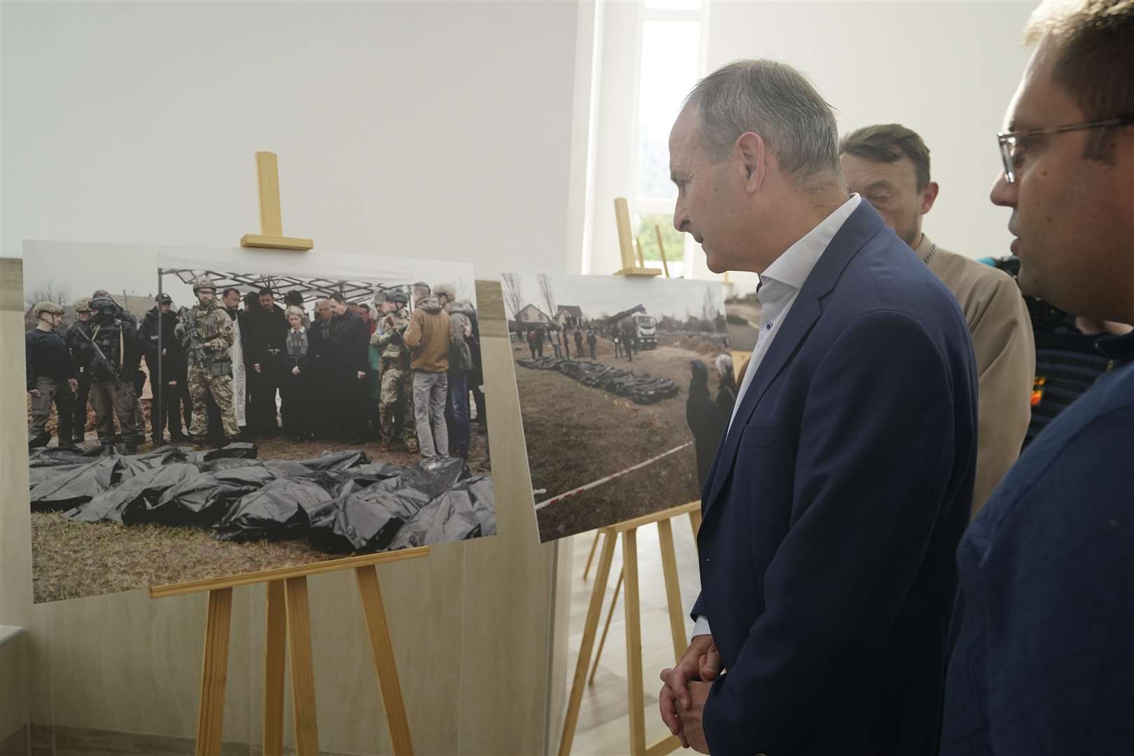Taoiseach Micheal Martin views an exhibition of photographs at the site of a mass grave found at the Church of St Andrew the First-Called in Bucha (Niall Carson/PA)