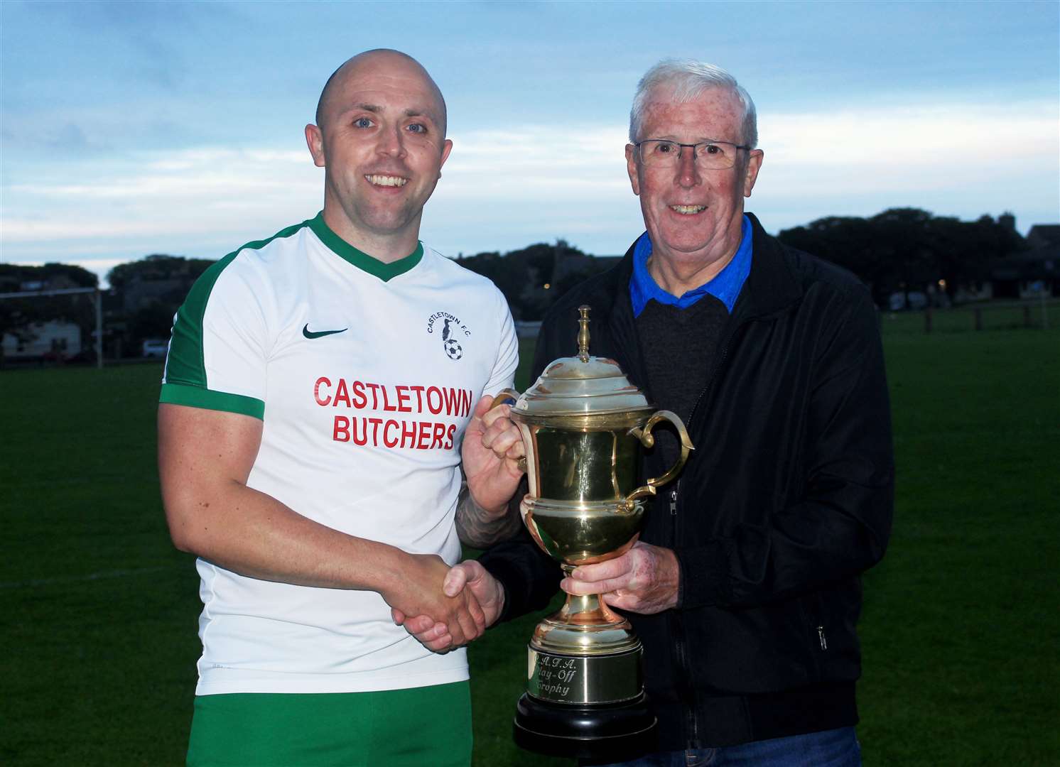 Castletown captain Danny Mackay receives the play-off trophy from Caithness AFA president Murray Coghill. Picture: Alan Hendry