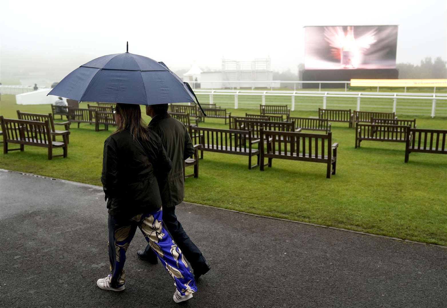 Racegoers shelter from the rain at Goodwood (Andrew Matthews/PA)