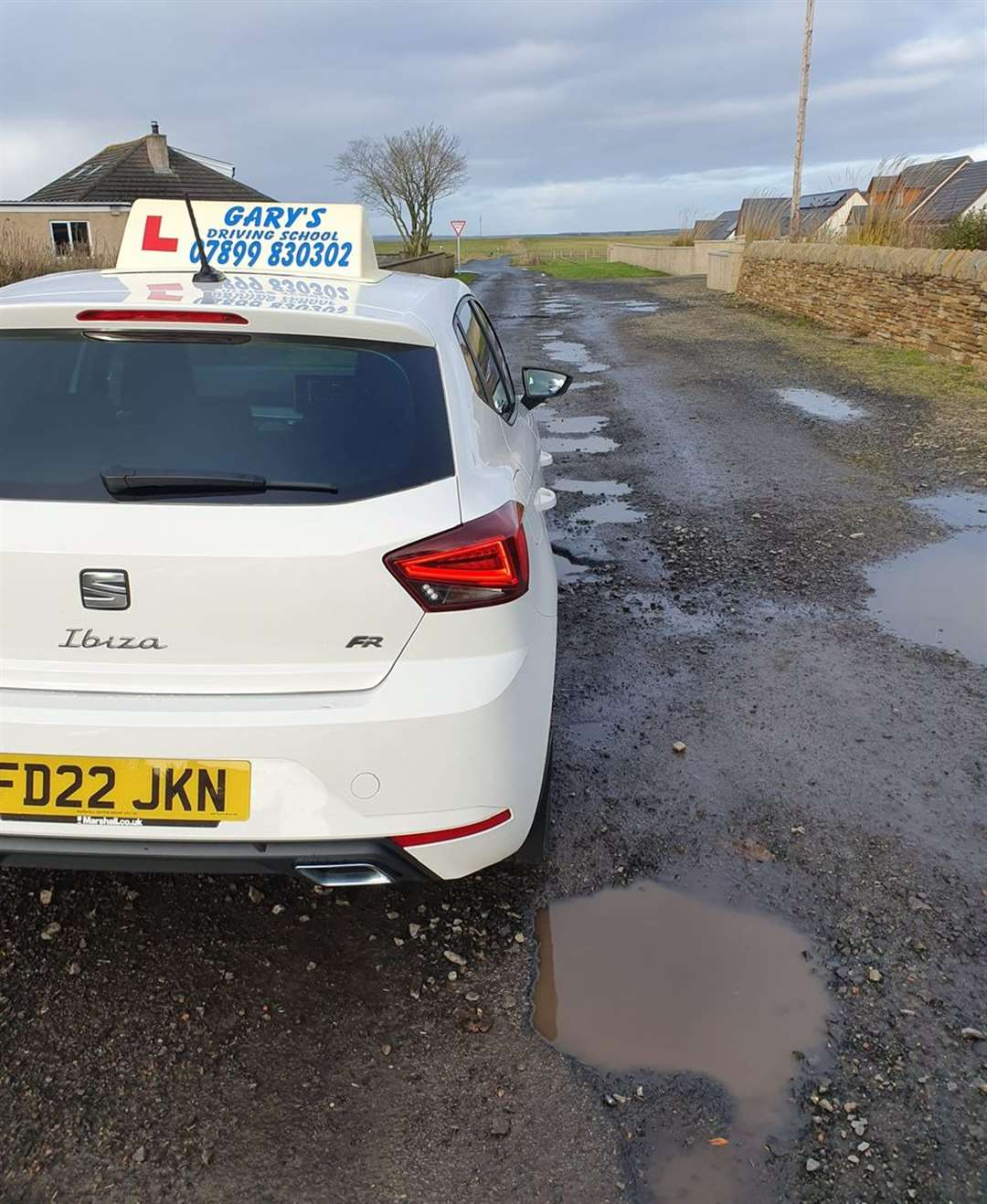 Gary Sinclair's car beside a potholed section of road at Newton Row.