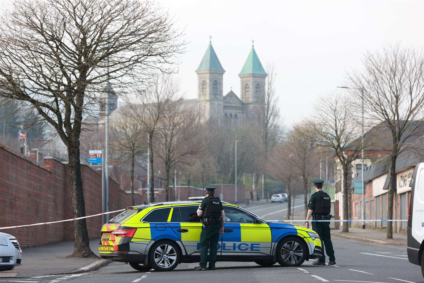 Officers from the PSNI looks across at Holy Cross church where emergency services are attending a security alert (Liam McBurney/PA)