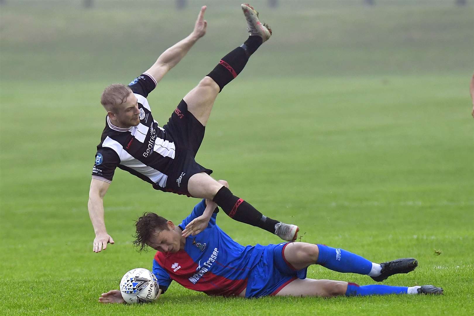 Millar Gamble's tackle sends Wick's two-goal hero Alan Hughes flying through the air. Picture: Mel Roger