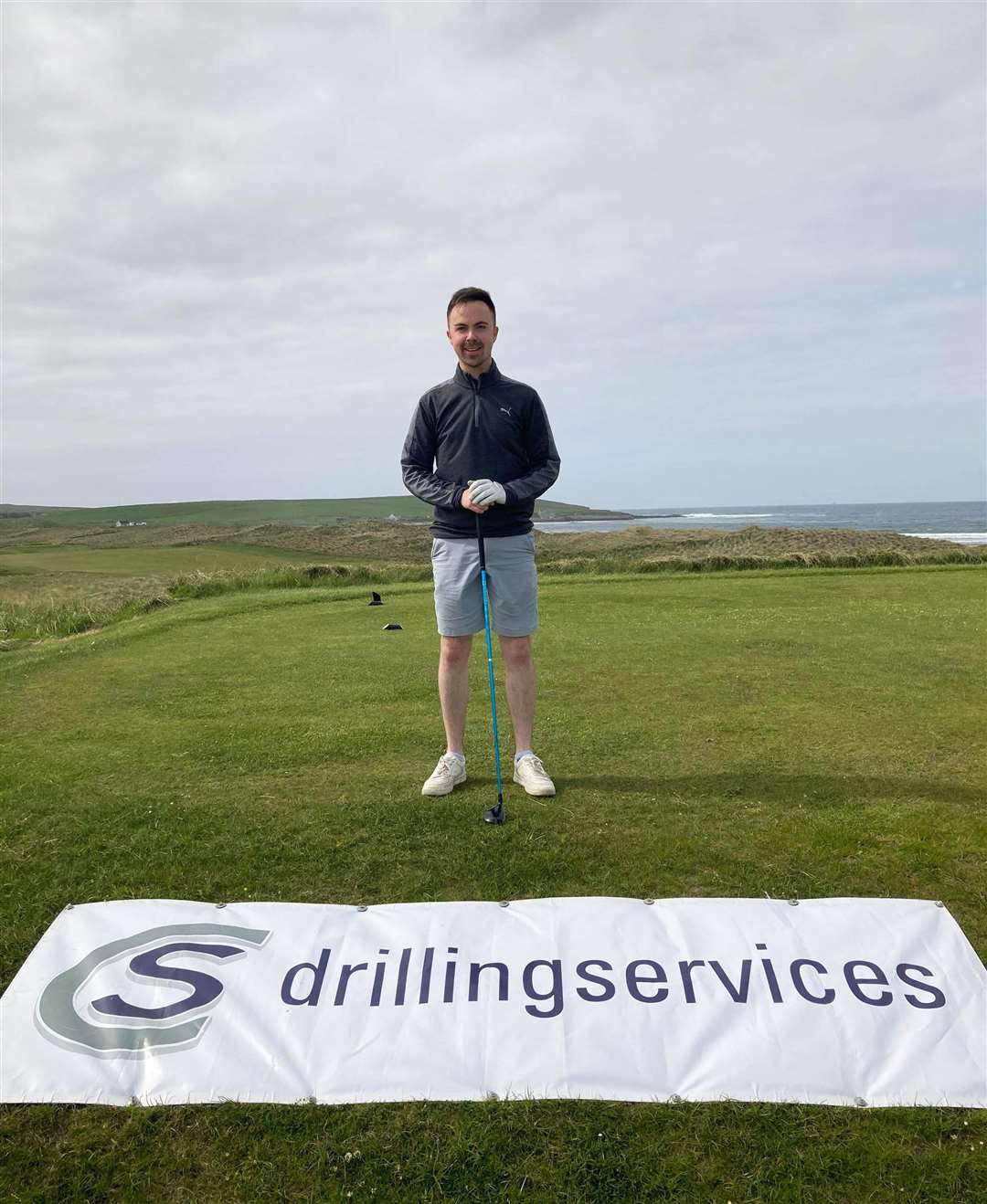 Gregor Munro, winner of the overall scratch prize at the NC500 Links Open on an aggregate score of 146, standing in front of a banner for day two sponsors CS Drilling Services.