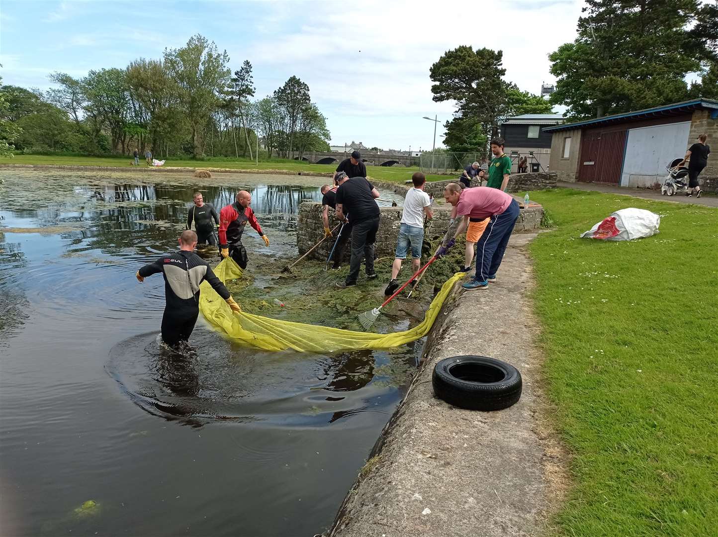 Volunteers used rakes and nets to clean the water and remove rubbish from the boating pond. Picture: Ron Gunn