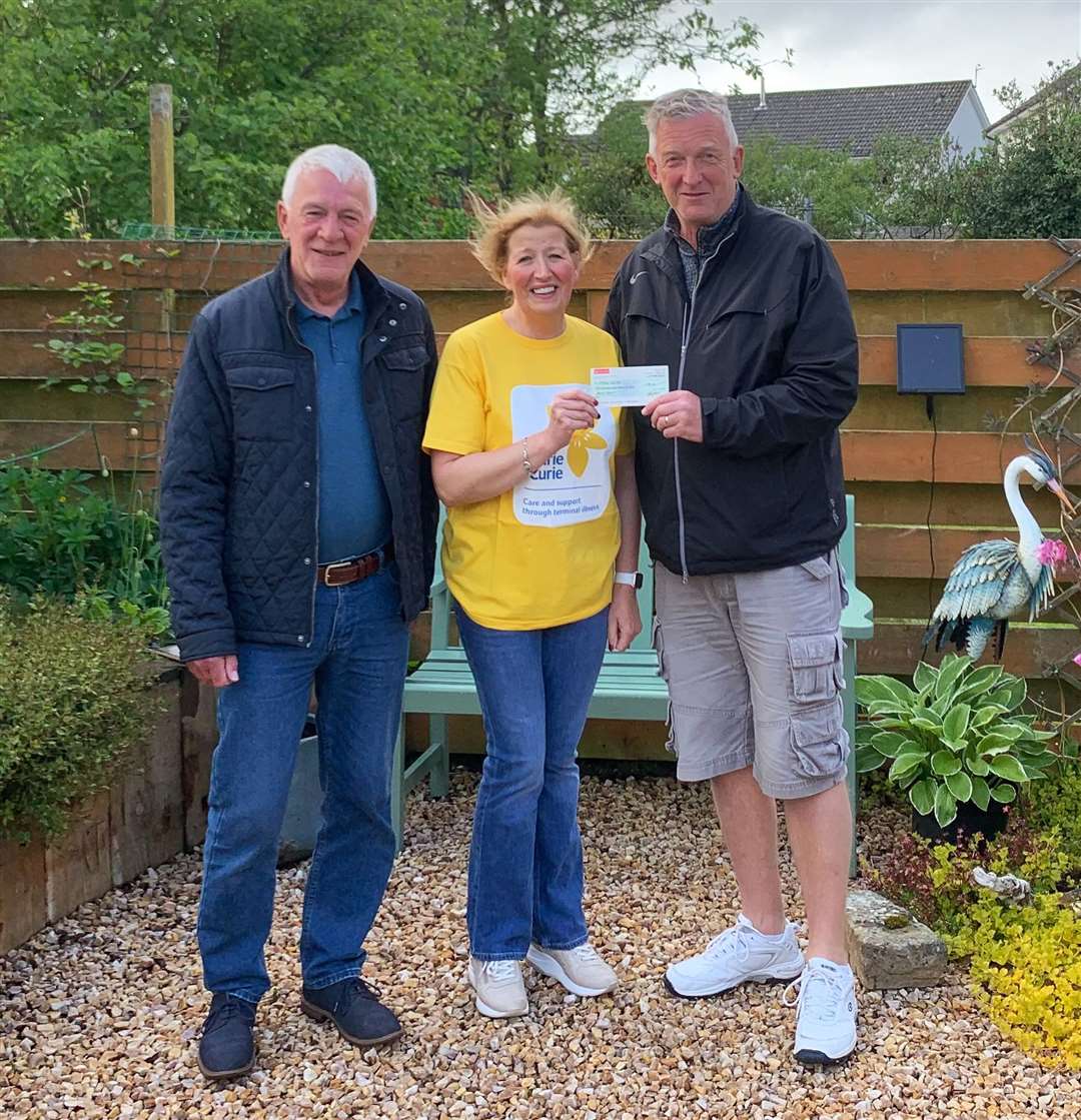 Organiser Sid Campbell presents the cheque to Christine Mackay, representing Marie Curie, while Brian Hutcheon looks on.