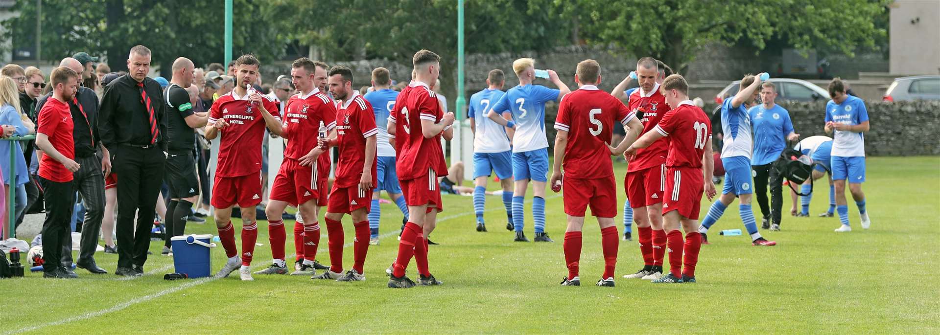 Players from Wick Groats and Wick Thistle take advantage of a water break due to the warm weather – a rare sight in Caithness football. Picture: James Gunn