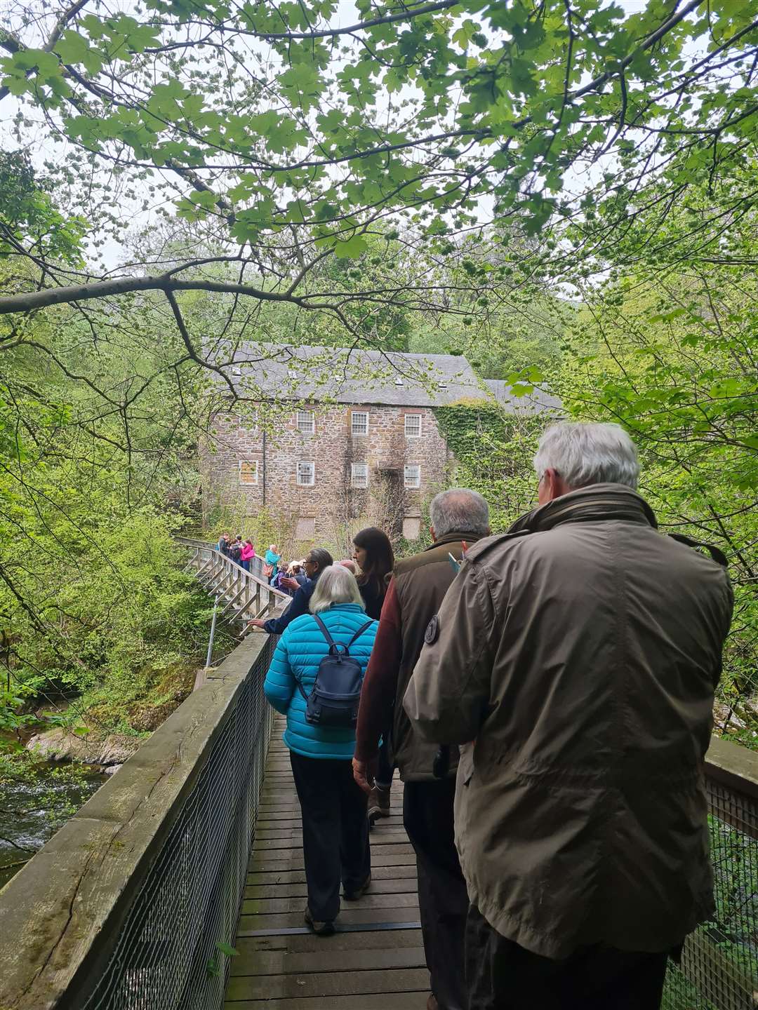 Conference delegates walking towards a historic mill on the River Ericht in Perthshire.