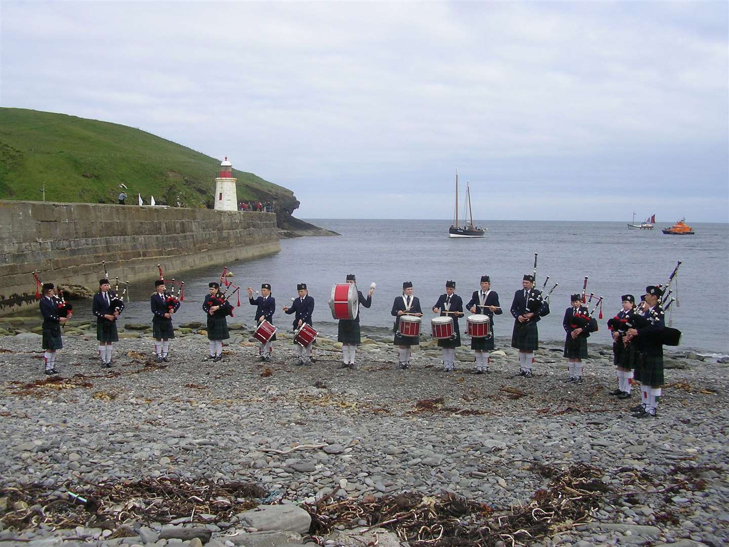 Caithness Junior Pipe Band playing on the shore at Lybster as part of HarbourFest in June 2007, with the historic Reaper entering the harbour.