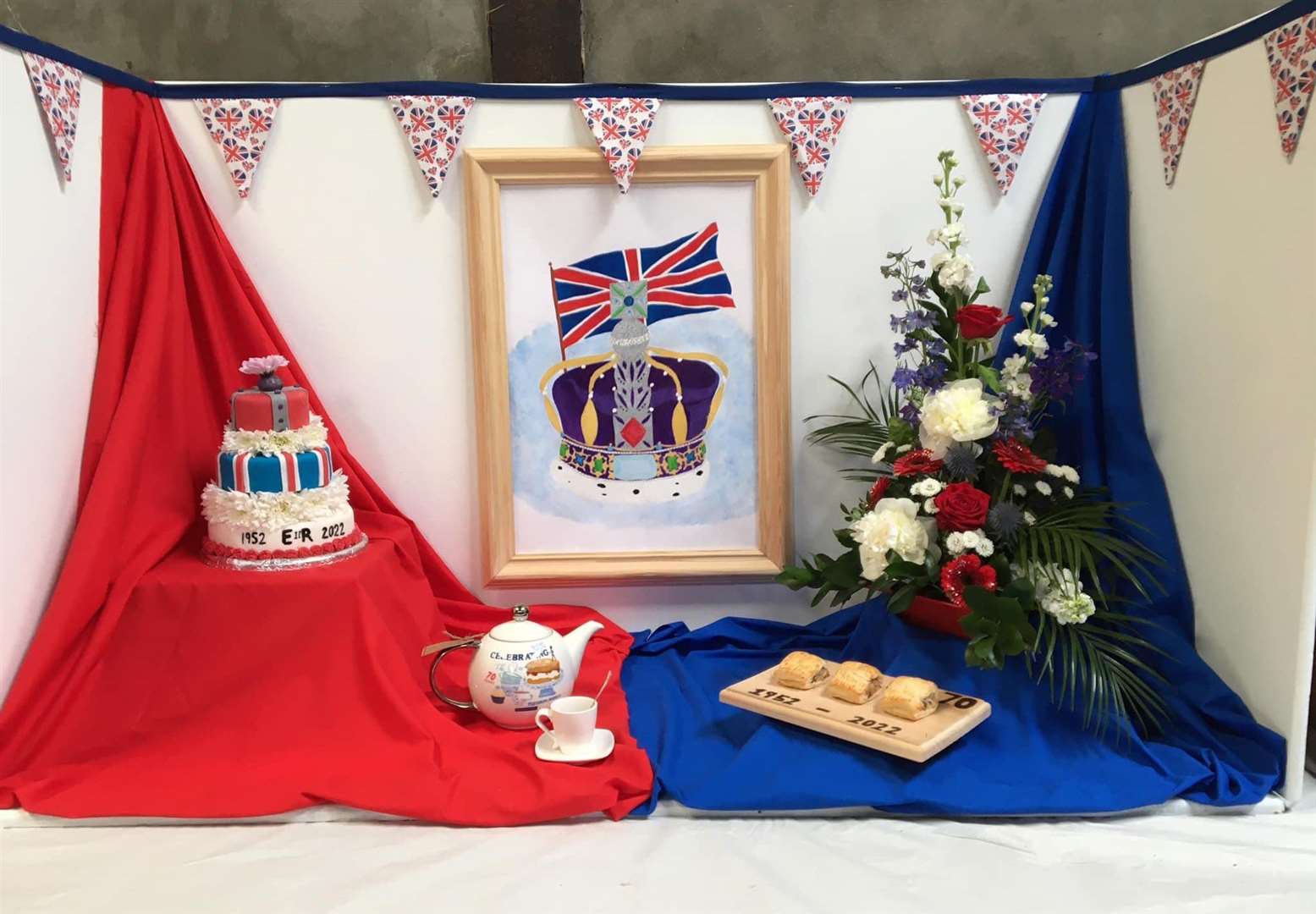 A jubilee theme to Bower's winning club display consisting of sausage rolls, decorated cake, floral arrangement, a mocktail, sewn bunting and a further article, a hand-drawn picture.