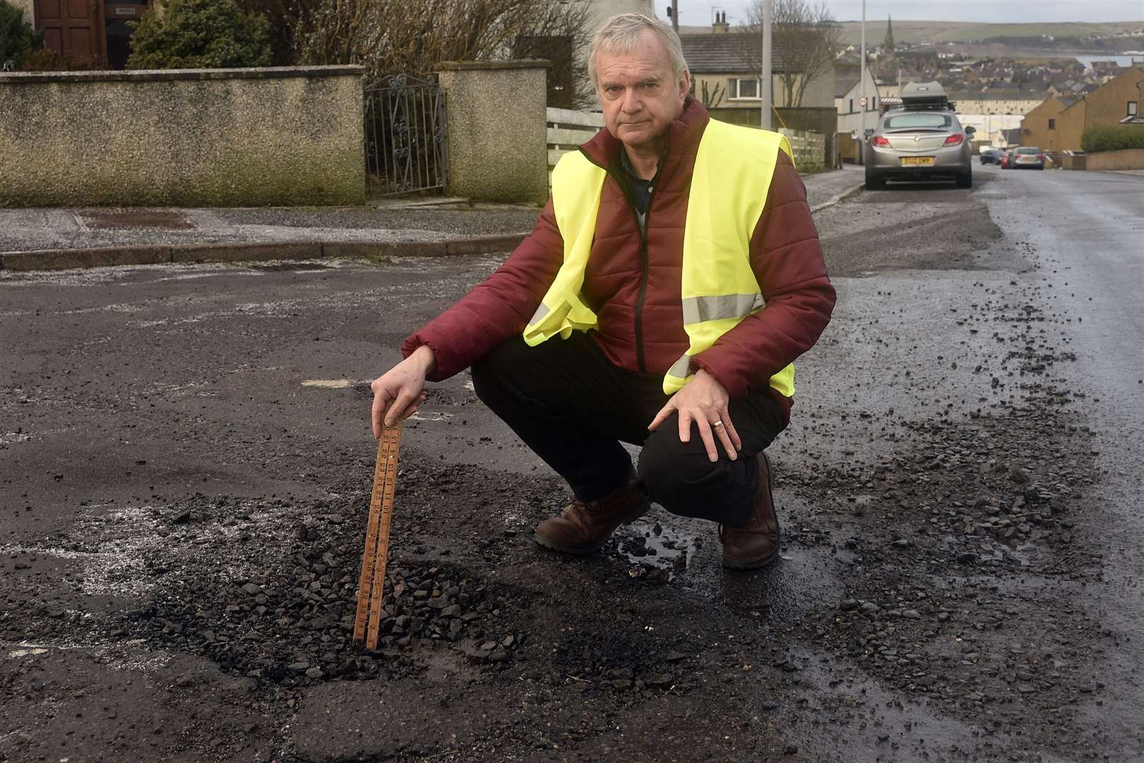 Councilor Ron Gunn measuring a pothole on Laurie Terrace on junction with Mount Pleasant Road. Picture: Mel Brooks