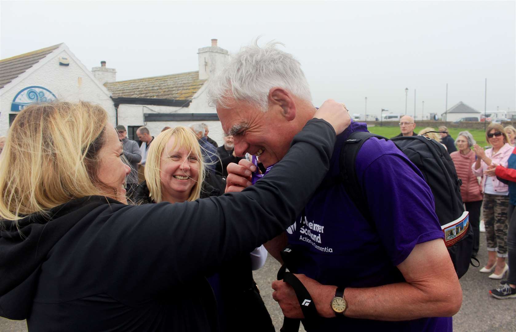 Susan Brass from Alzheimer Scotland hangs a medal around Frank’s neck as Isobel Stevenson looks on. Picture: Alan Hendry