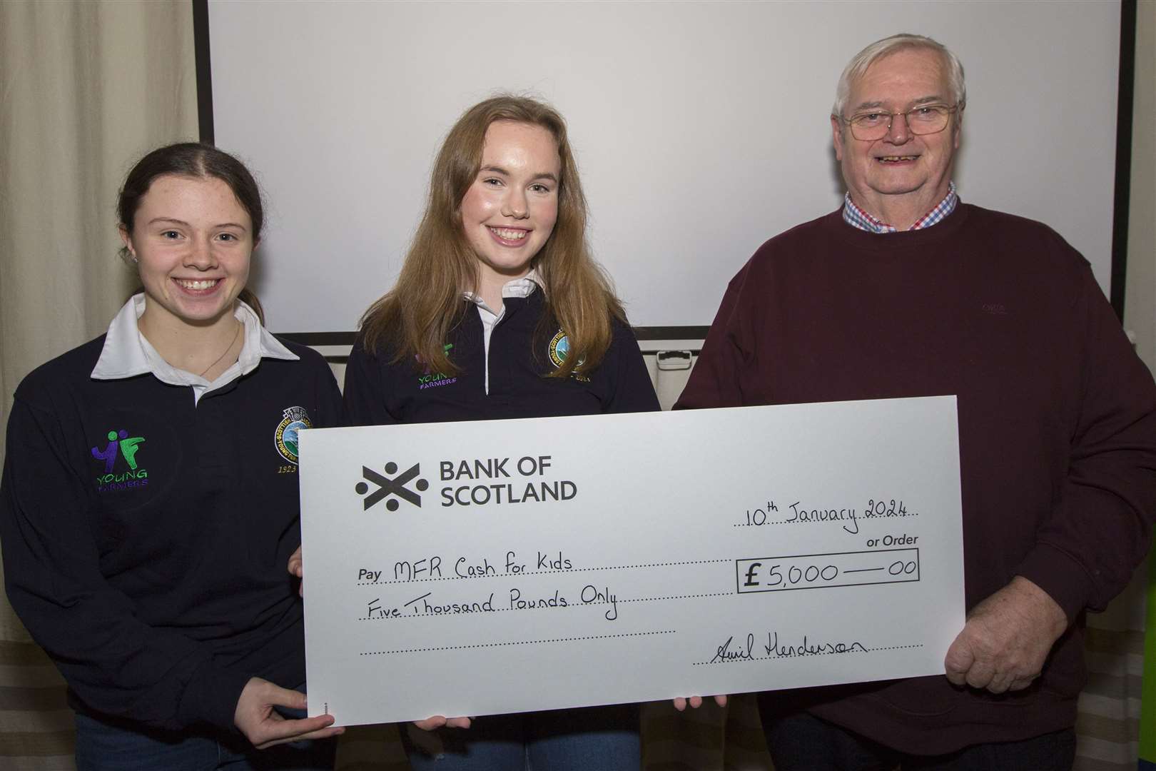 Chloe Begg (left), of Halkirk Young Farmers, and Isla Mackay, Bower, present the MFR Cash For Kids cheque to Will Gunn, who accepted it on behalf of the charity. Picture: Robert MacDonald / Northern Studios