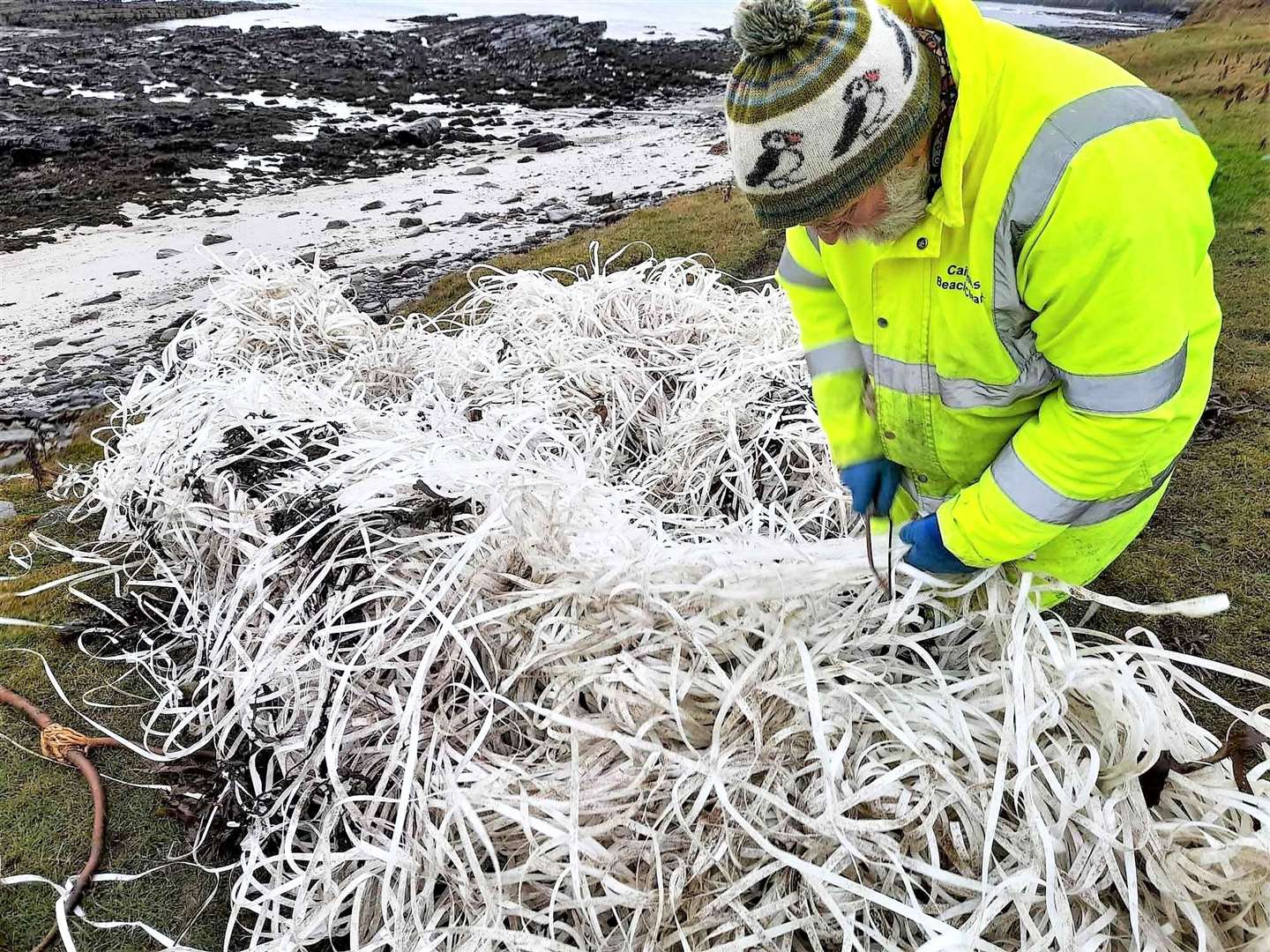 Allan with the 10-mile bundle of pallet strapping removed from Ackergill shore last December.