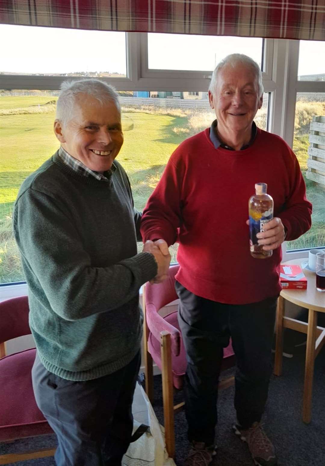 Colin Struthers (right) receives the nearest-the-pin prize, a bottle of North Point rum, from senior convener Sandy Chisholm after the latest round of the seniors' winter Stableford competition at Reay.