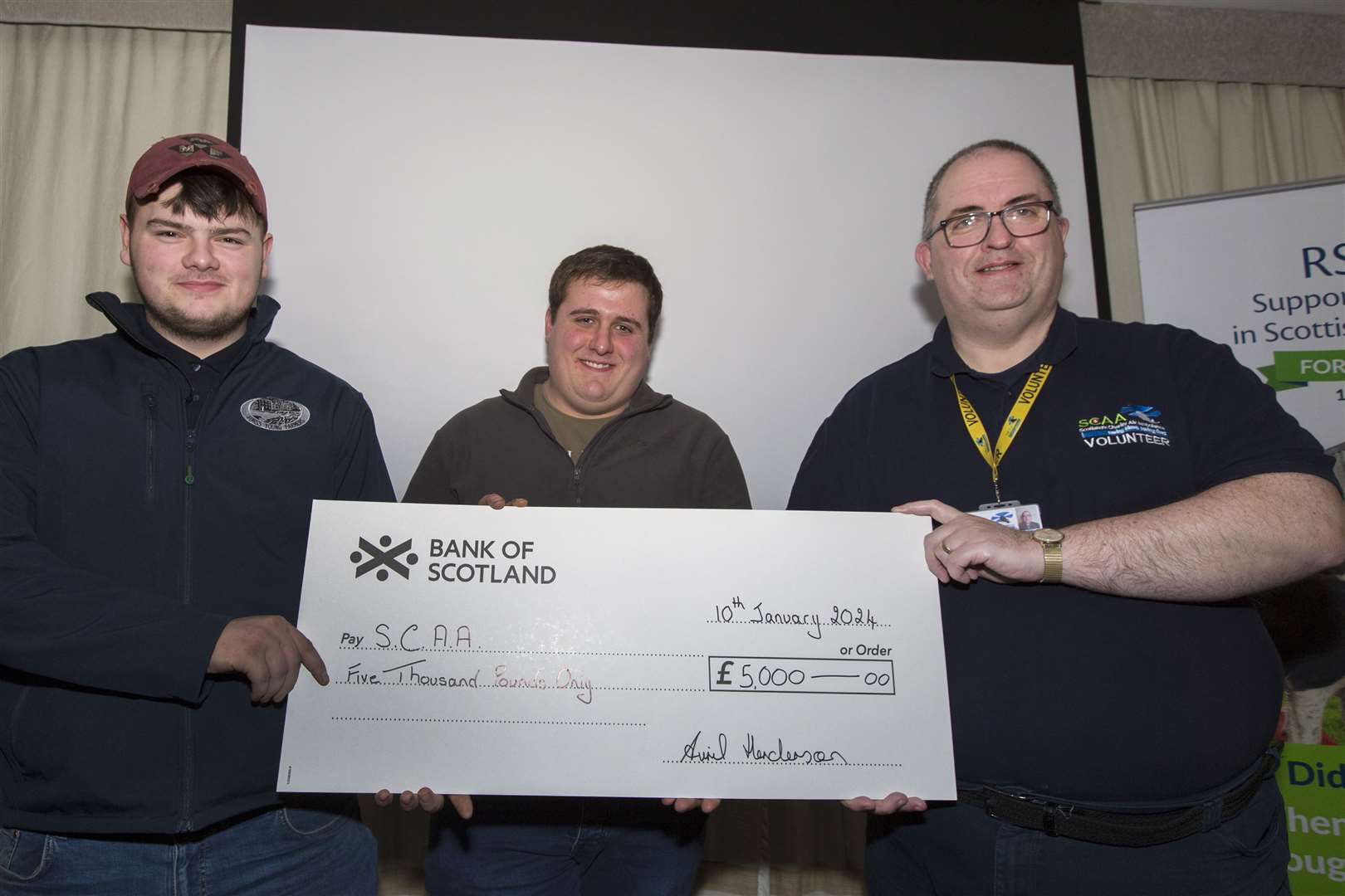 Matthew Murray (left), of Forss Young Farmers, and William Campbell, Bower, present a £5000 cheque to Gavin Geddes (right), a volunteer with Scotland's Charity Air Ambulance. Picture: Robert MacDonald / Northern Studios