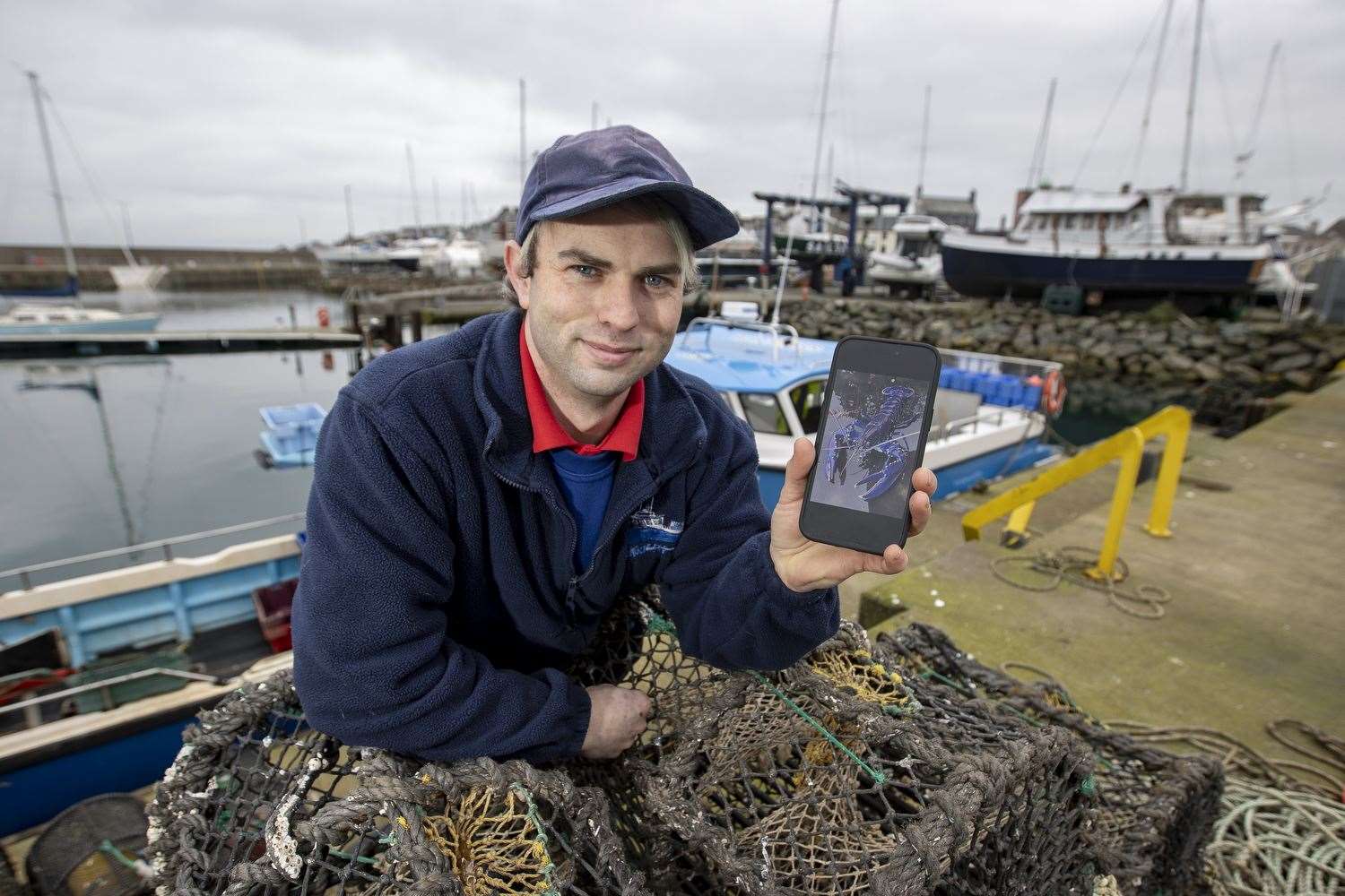 Stuart Brown, skipper of the Huntress fishing boat, shows a picture of the blue lobster (Liam McBurney/PA)
