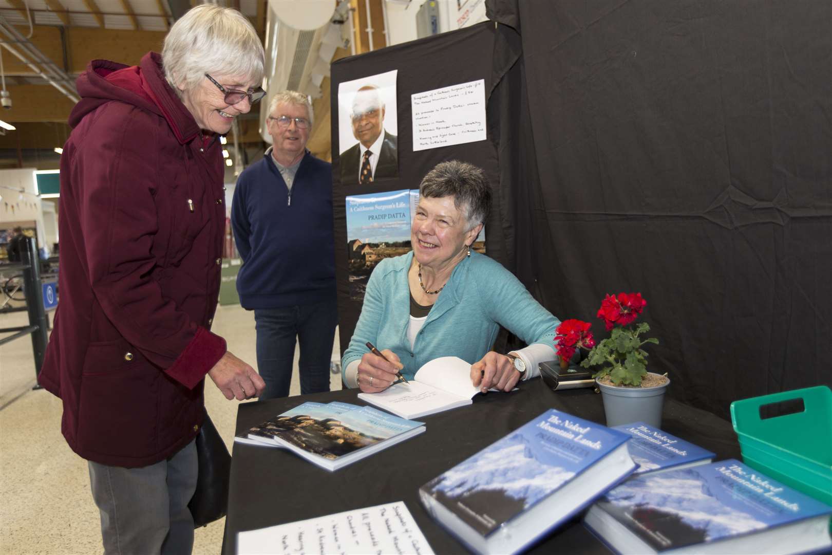 Dr Loretta Davis-Reynolds signs a copy of Snapshots of a Caithness Surgeon's Life for Elizabeth Innes, while Roy Mackenzie looks on. Picture: Robert MacDonald / Northern Studios