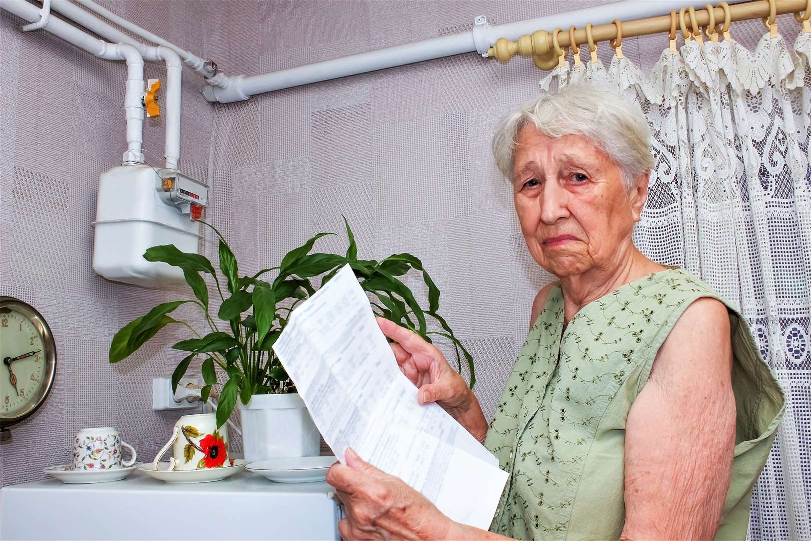 The sad senior woman at home and examines gas bill. She is under stress when checking accounts.