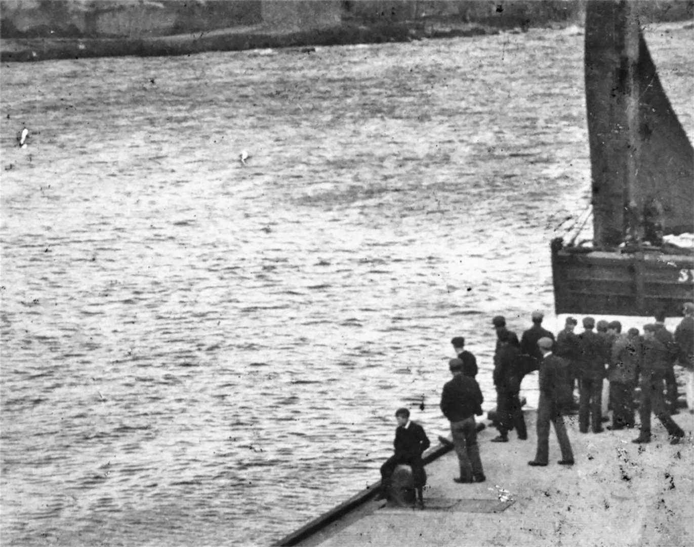 This scene shows men watching a boat enter Wick harbour.