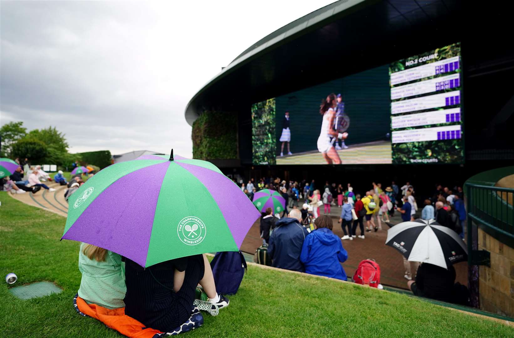 Spectators shelter from the rain on day two of the 2023 Wimbledon Championships (Zac Goodwin/PA)