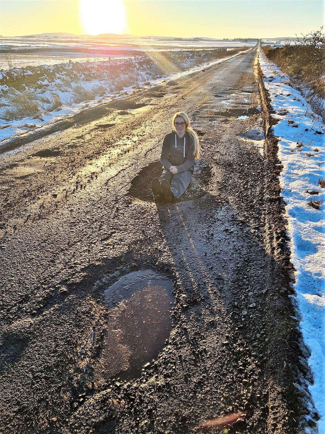 Megan Gillon sits in the monster pothole that wrecked two wheels of her car. Pictures: Kirsty Gillon