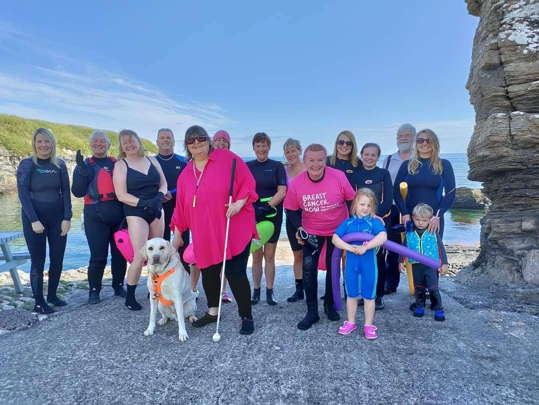 Lesley and the group of swimmers at Staxigoe Harbour. She is with her daughter Erica and grandchildren as well as her friend, Caron Jones, who is accompanied by her guide dog Qantas.