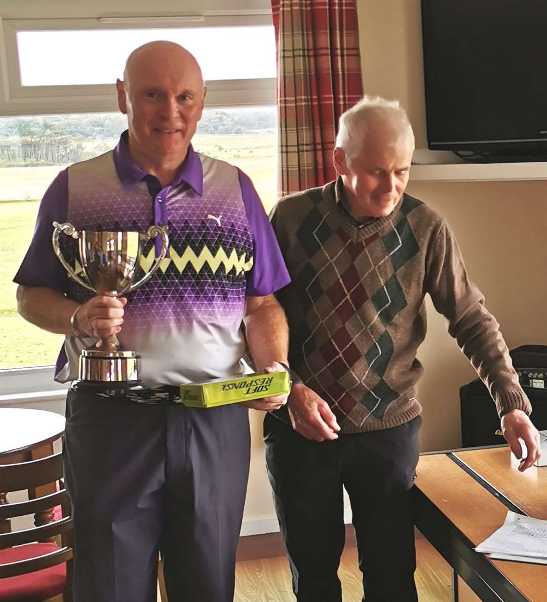 Stuart Greig receives the Evan Sutherland Trophy and first prize for the Reay seniors' summer eclectic competition from Sandy Chisholm.