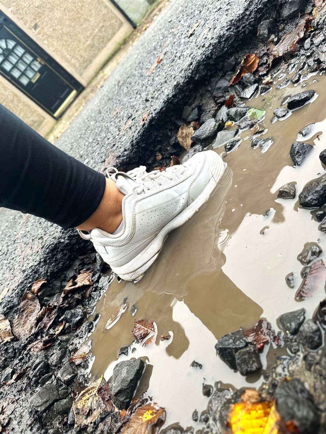 Alison puts her foot in the pothole at Argyle Square which is several inches deep and is part of a series of potholes on the street that stretch for many yards.
