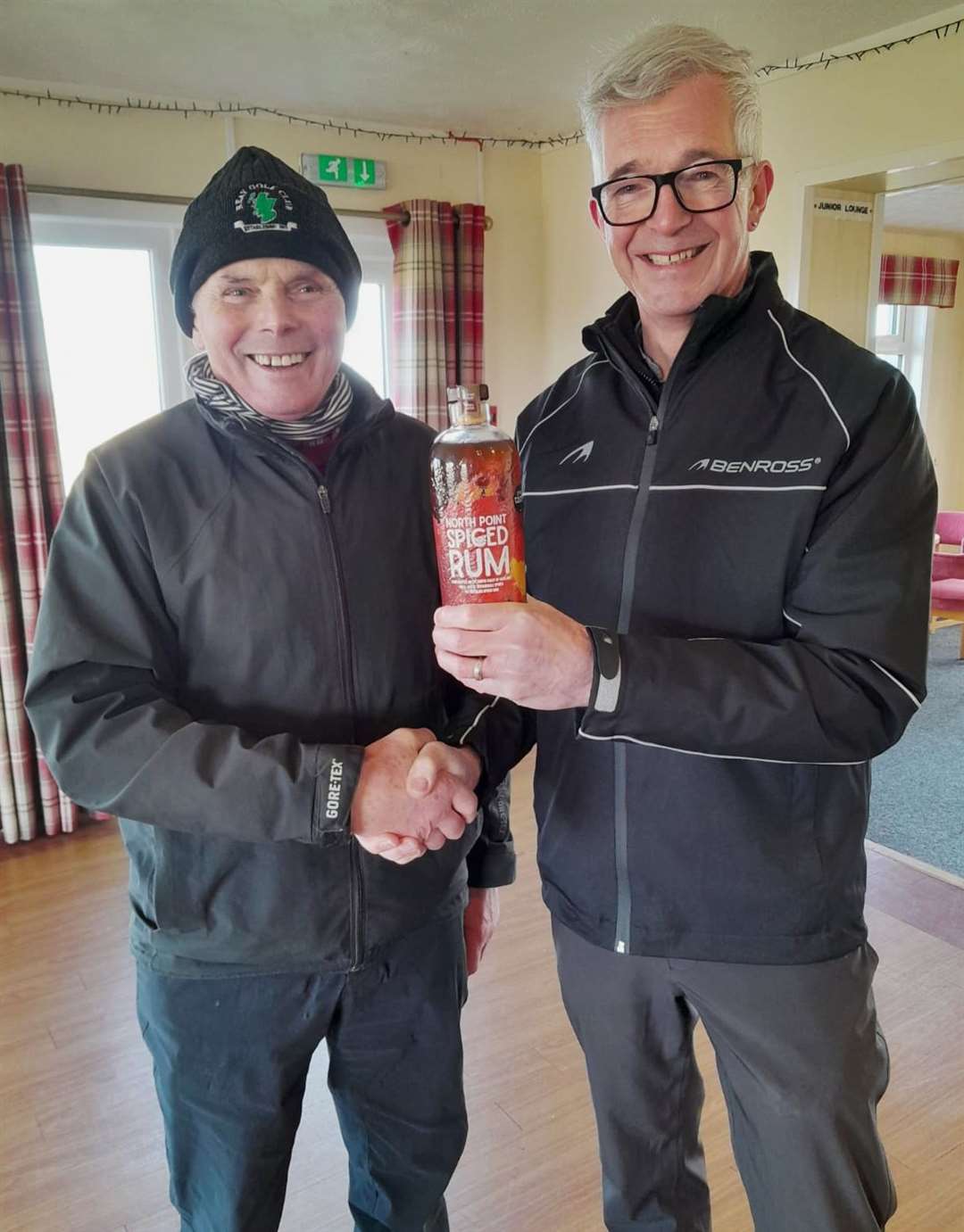 David R Craig (right), winner of the February nearest-the-pin prize in the North Point Distillery Senior Stableford competition, receiving a bottle of rum from seniors convener Sandy Chisholm.