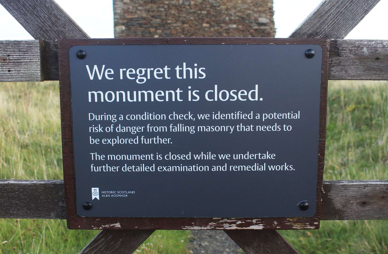 A sign attached to the wooden gate at the entrance to the castle site.