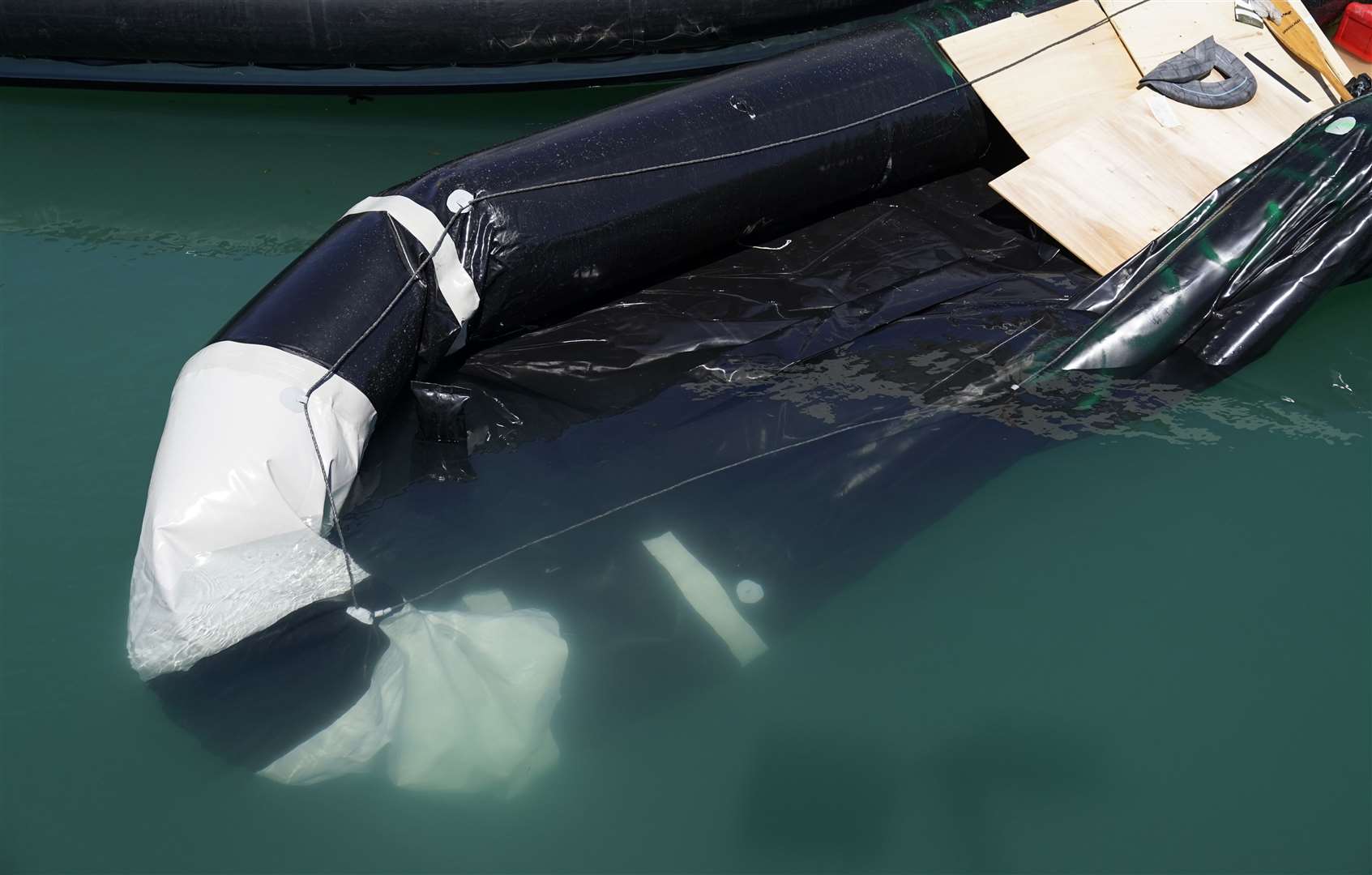 A partially submerged inflatable boat is brought into the marina after a group of people thought to be migrants are brought in to Dover, Kent, by Border Force (Andrew Matthews/PA)