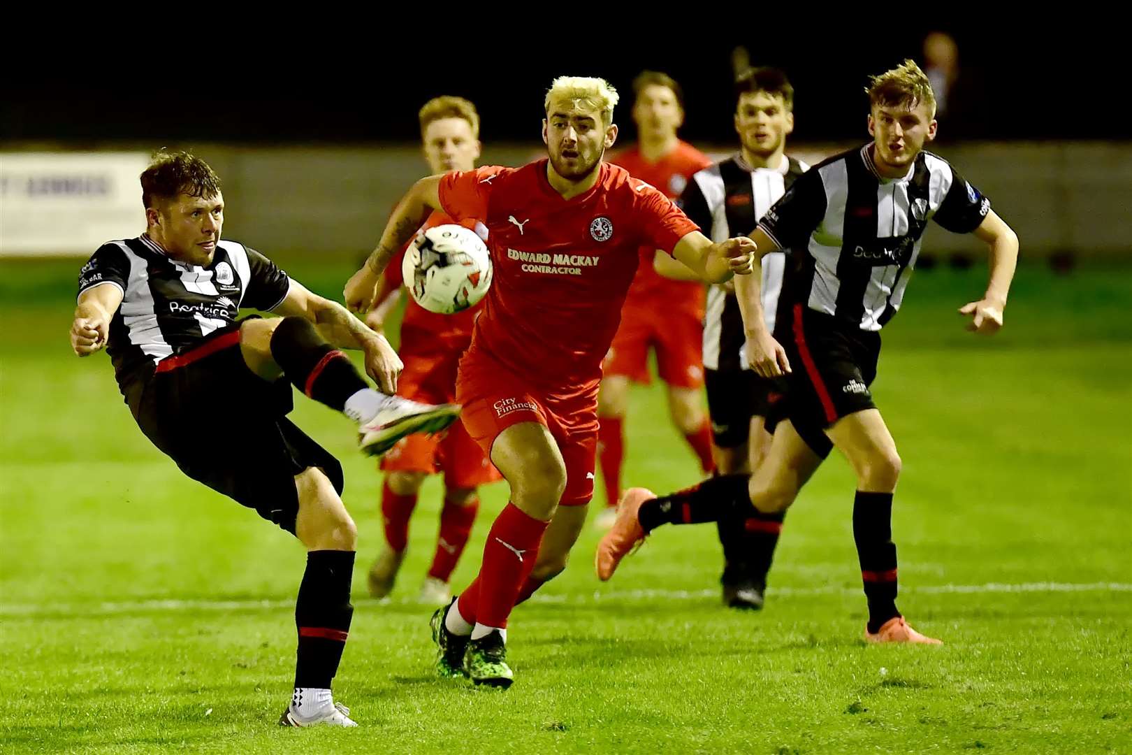 Wick Academy's Jack Henry focuses on clearing the ball as Brora substitute Jordan MacRae looks on. Picture: Mel Roger
