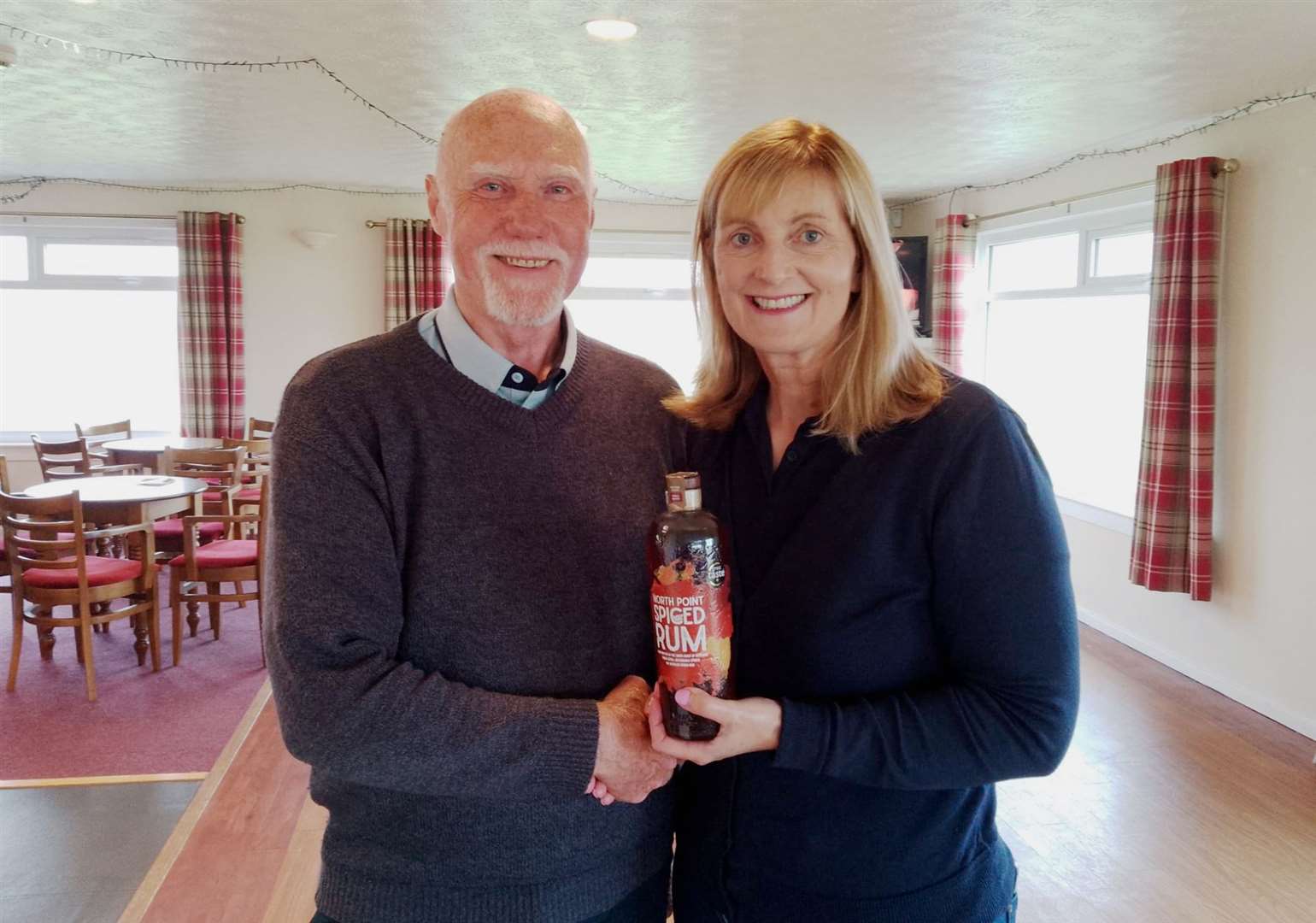 Pete Barker receives a bottle of North Point Distillery spiced rum from Carol Paterson after he won the nearest-the-pin prize in the latest round of the Senior Stableford competition.