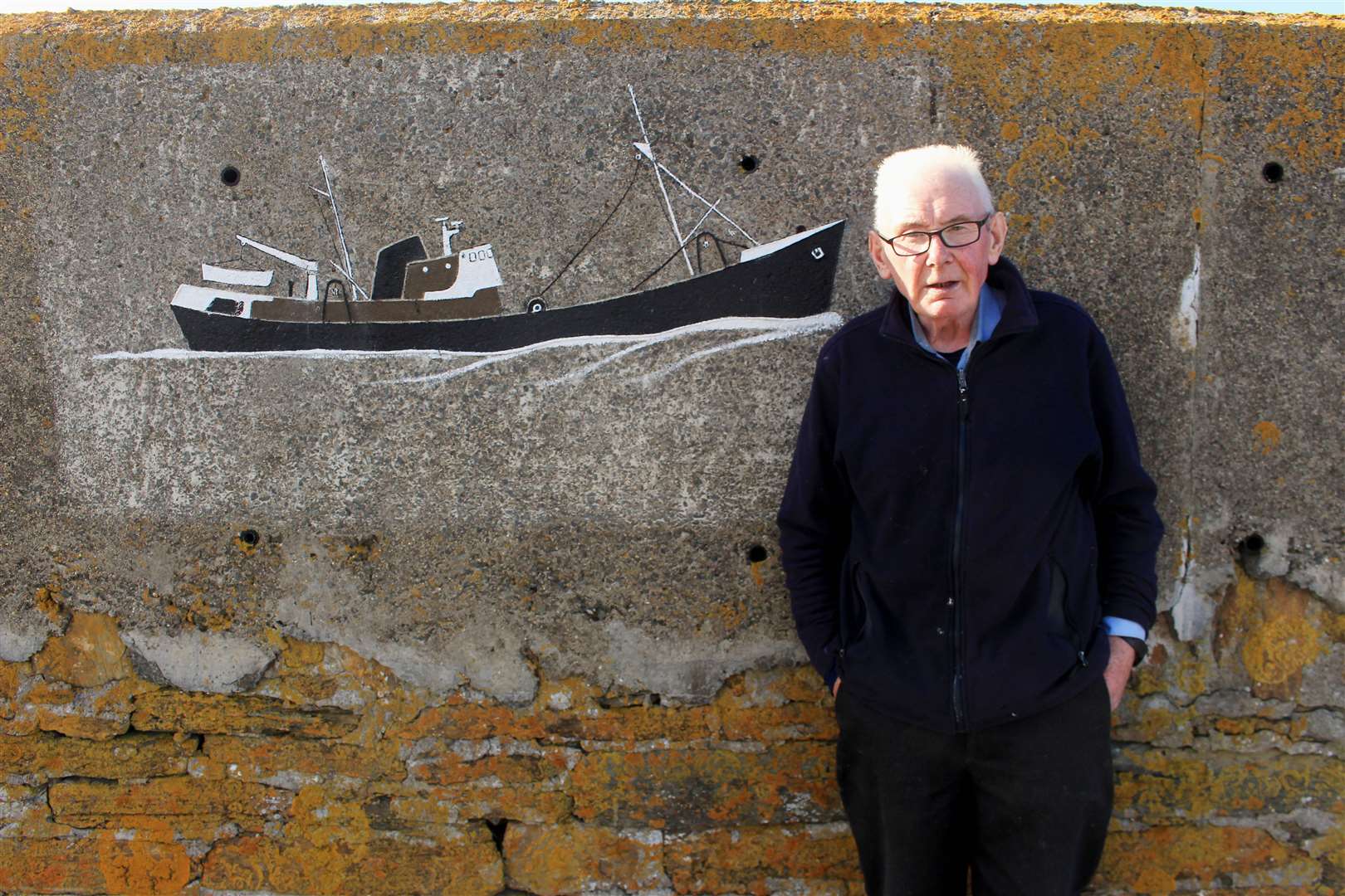 Derry Ross beside one of his fishing boat designs on the concrete wall at Phillip's Harbour. Picture: Alan Hendry