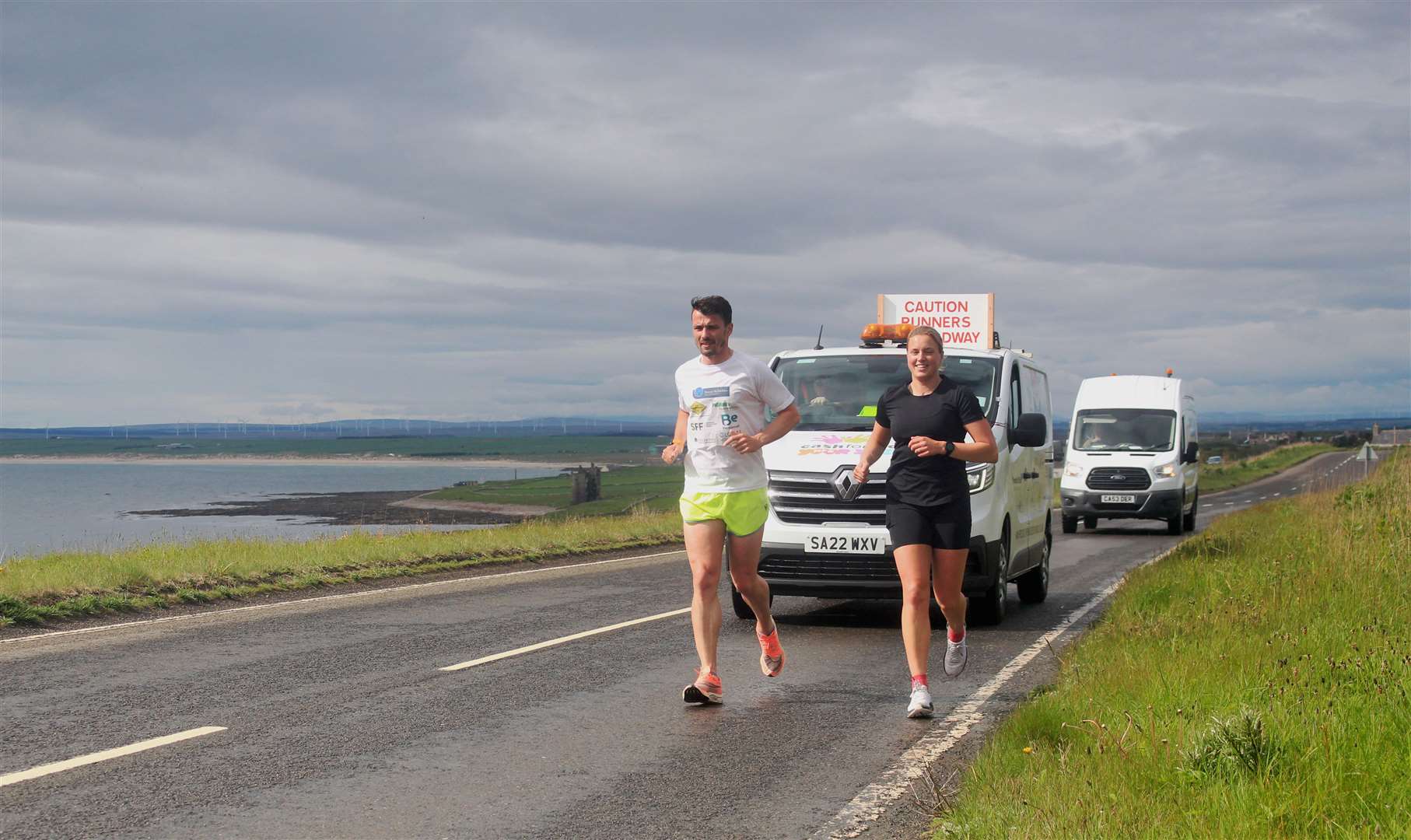 Steven Mackay and fellow runner Seana Forbes making their way past Sinclair's Bay, with Keiss Castle in the distance. Picture: Alan Hendry