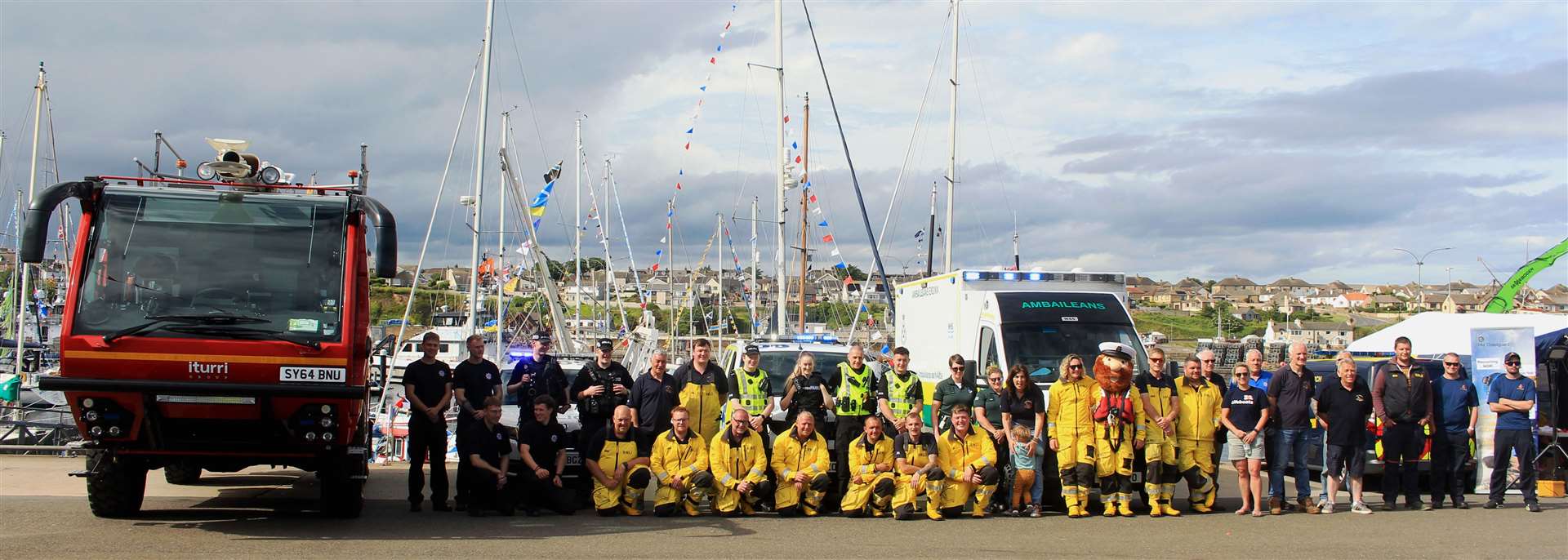 Wick lifeboat crew members (and RNLI mascot Stormy Stan) line up with representatives of the emergency services who took part in Harbour Day 2023. Picture: Alan Hendry