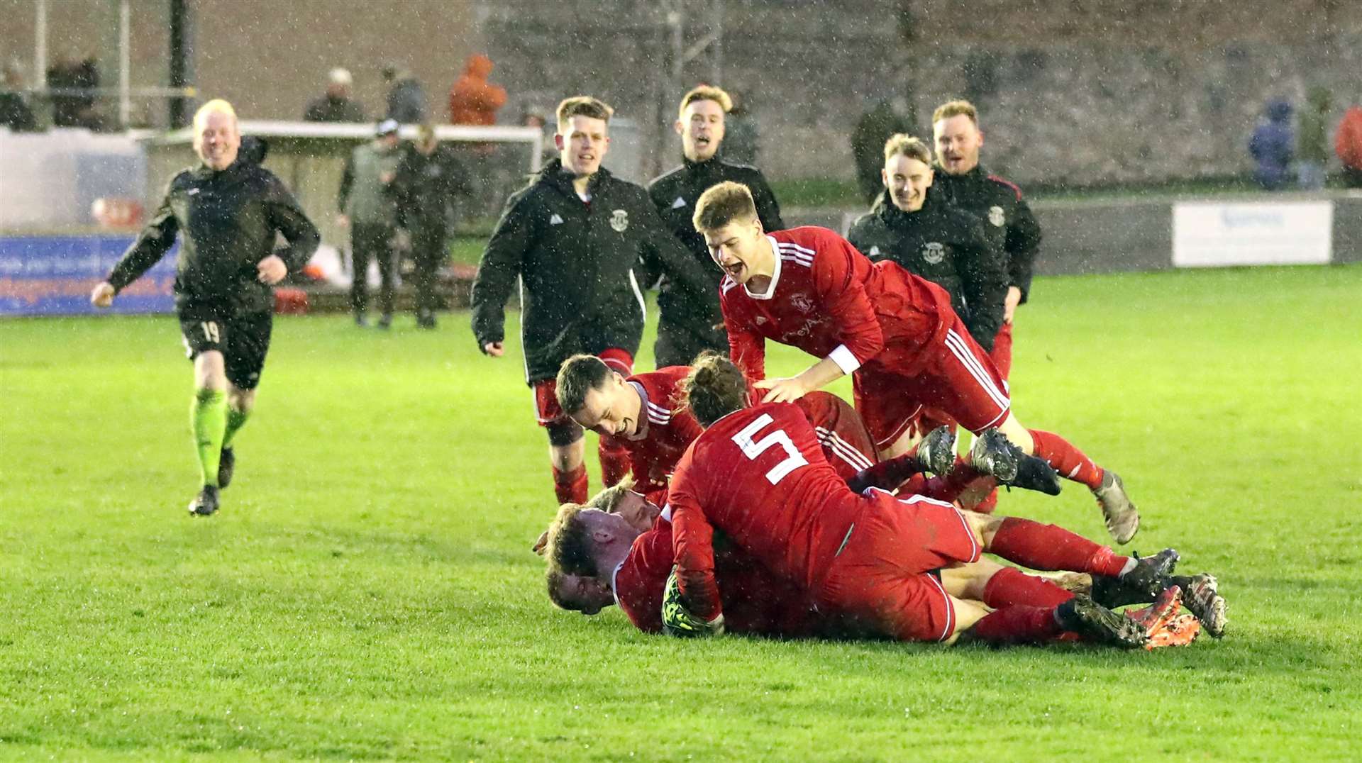 Thurso players pile on top of keeper Asa Sinclair after he saved two penalties in the shoot-out. Picture: James Gunn
