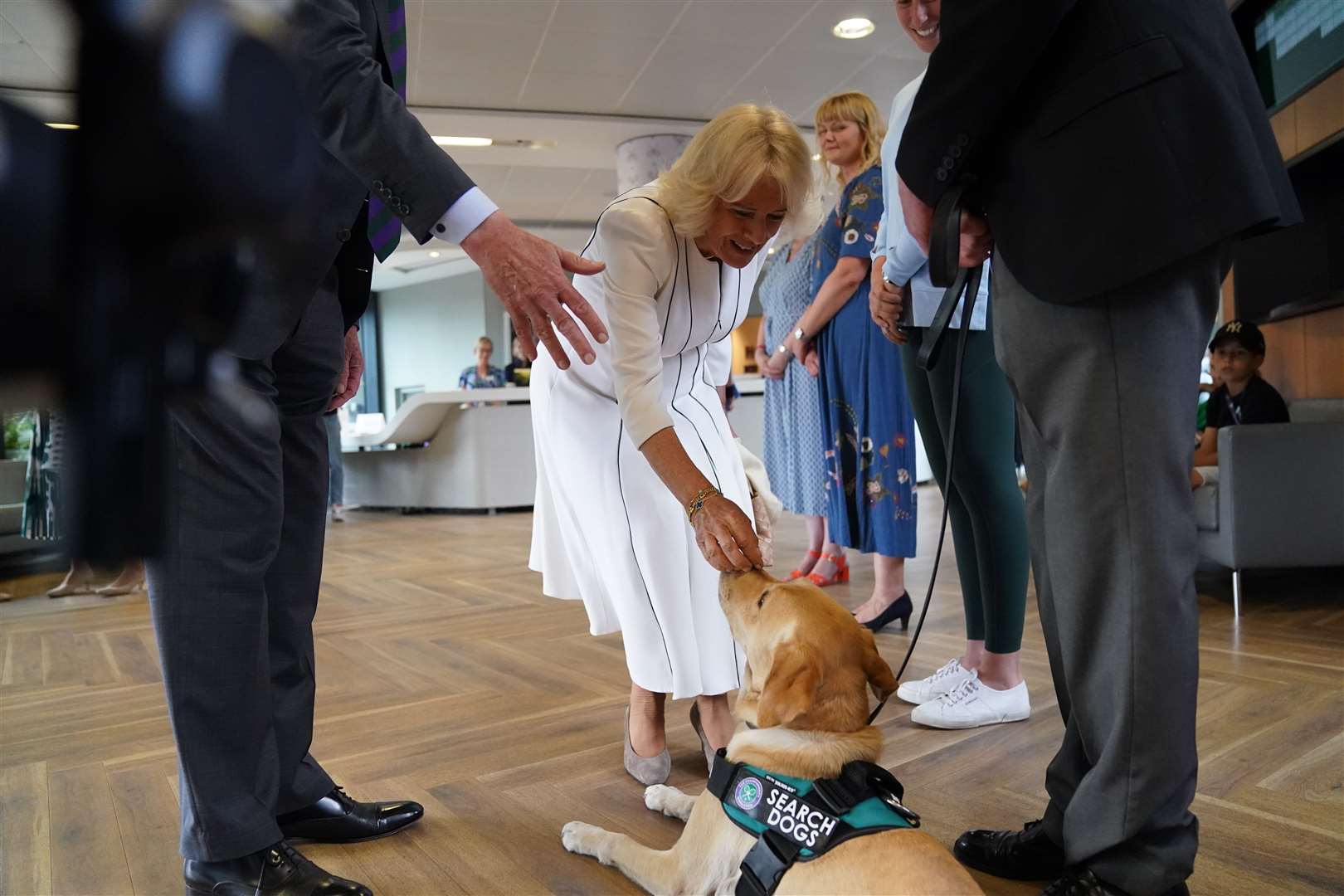 Camilla leans down to pat Flo, part of the security team at Wimbledon (Victoria Jones/PA)