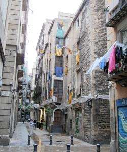 Catalan and EU flags are displayed from buildings in this street in the old town in Barcelona.