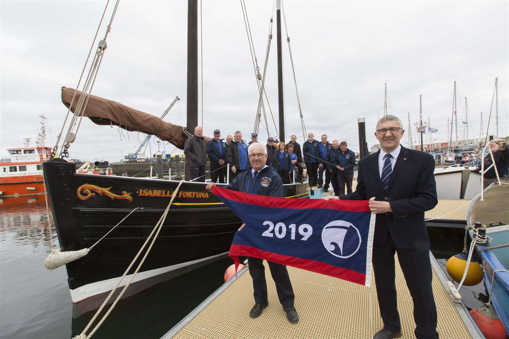 The regional flagship pennant is handed over to the Isabella Fortuna's skipper Malcolm Bremner (left) by Vice Lord-Lieutenant Willie Watt. Looking on are some of the crew and volunteers who sail and look after the historic vessel. Picture: Robert MacDonald / Northern Studios